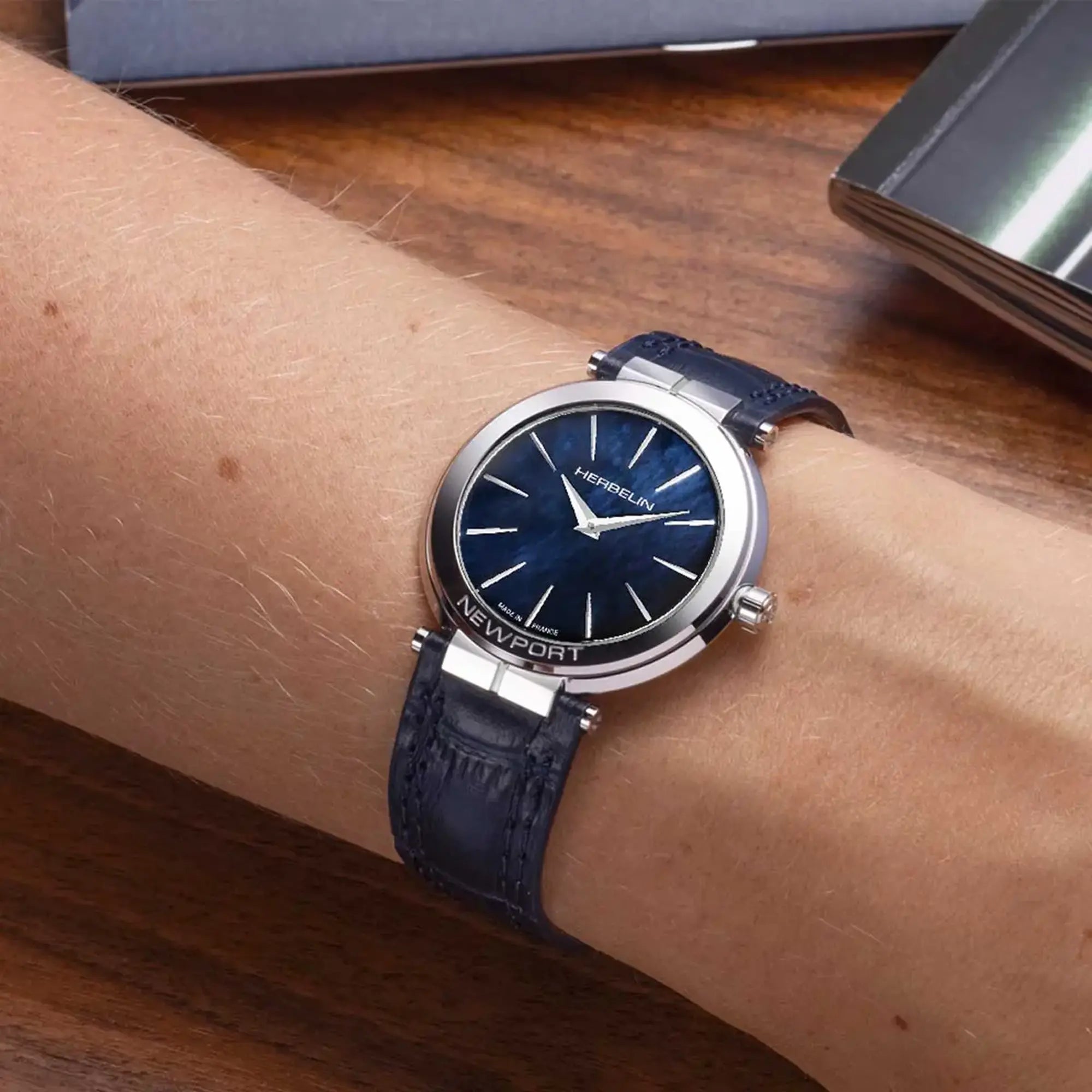 Au poignet féminin, cadran nacre bleue et bracelet cuir visibles
