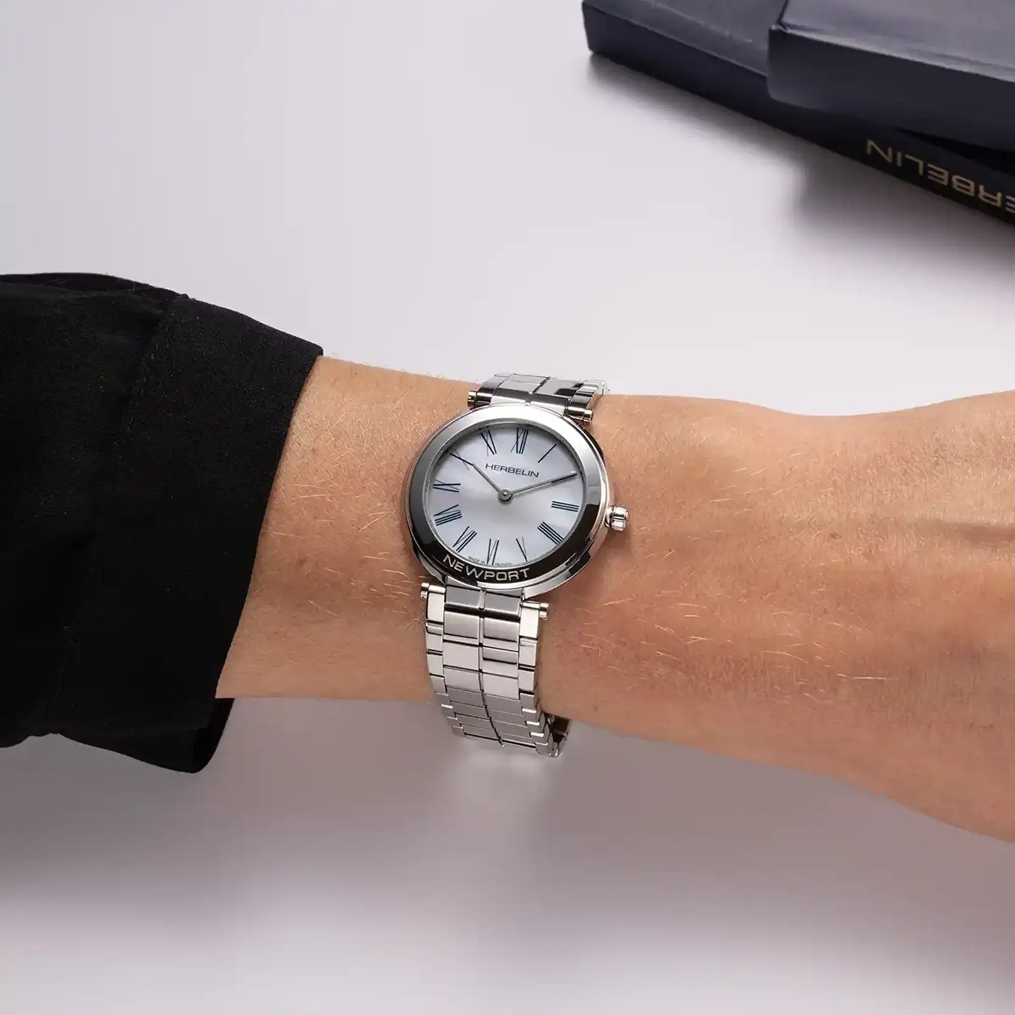 Au poignet féminin, cadran nacre blanche et bracelet acier visibles