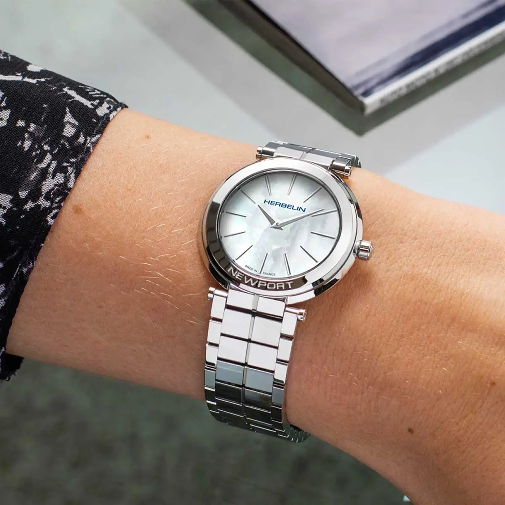 Au poignet féminin, cadran nacre blanche et bracelet acier visibles