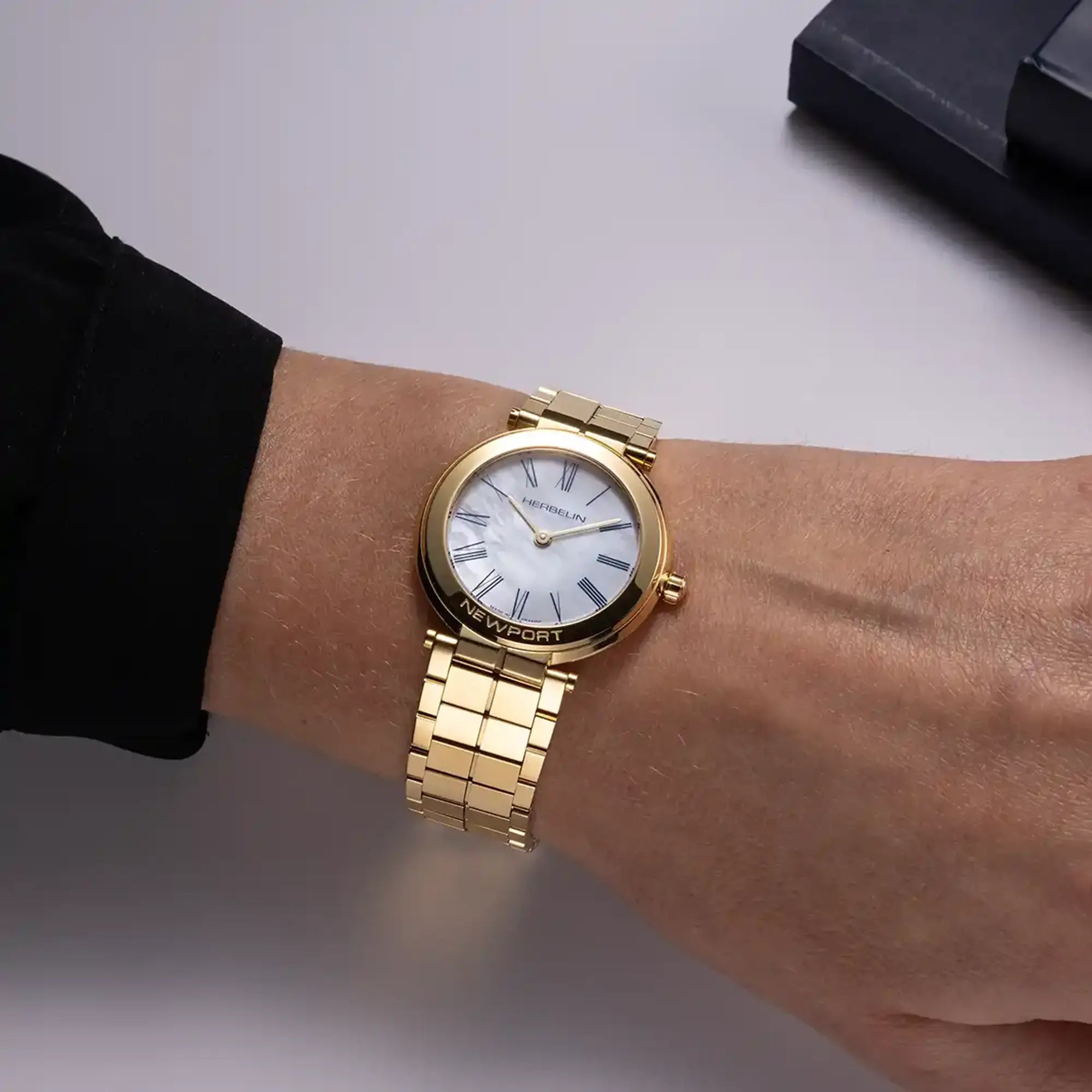 Au poignet féminin, cadran nacre blanche et bracelet acier bicolore visibles