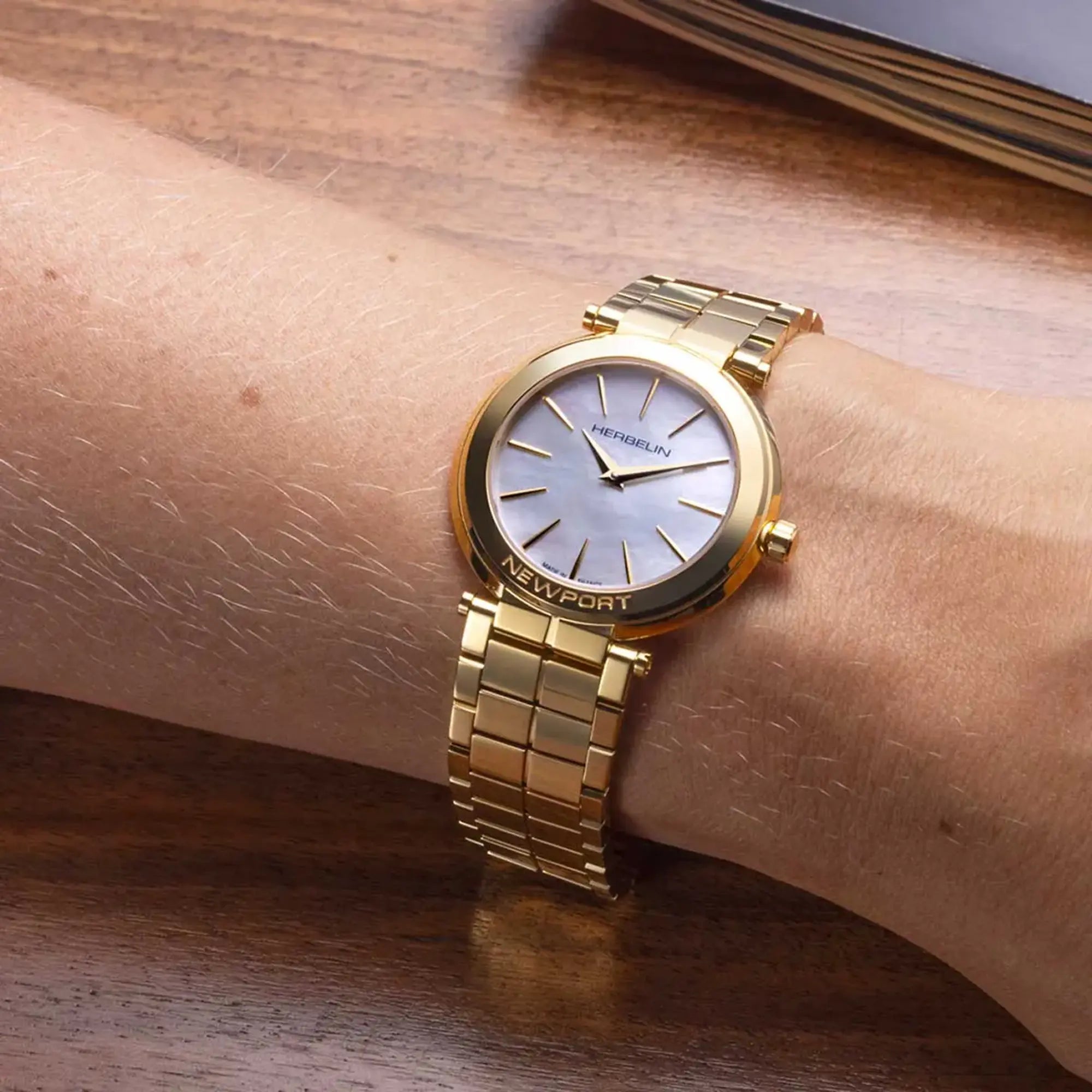 Au poignet féminin, cadran nacre blanche et bracelet acier bicolore visibles