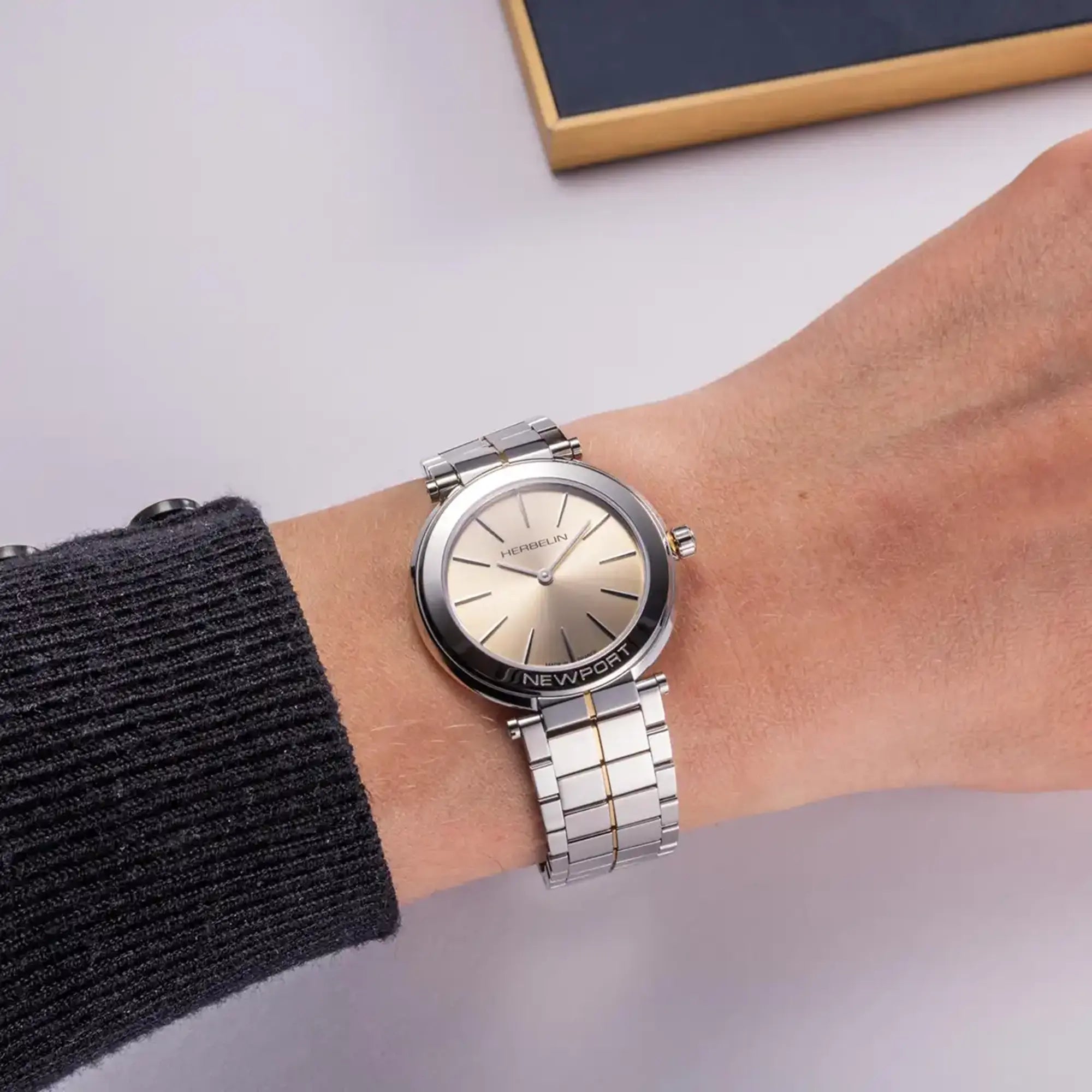 Au poignet féminin, cadran champagne et bracelet acier bicolore visibles