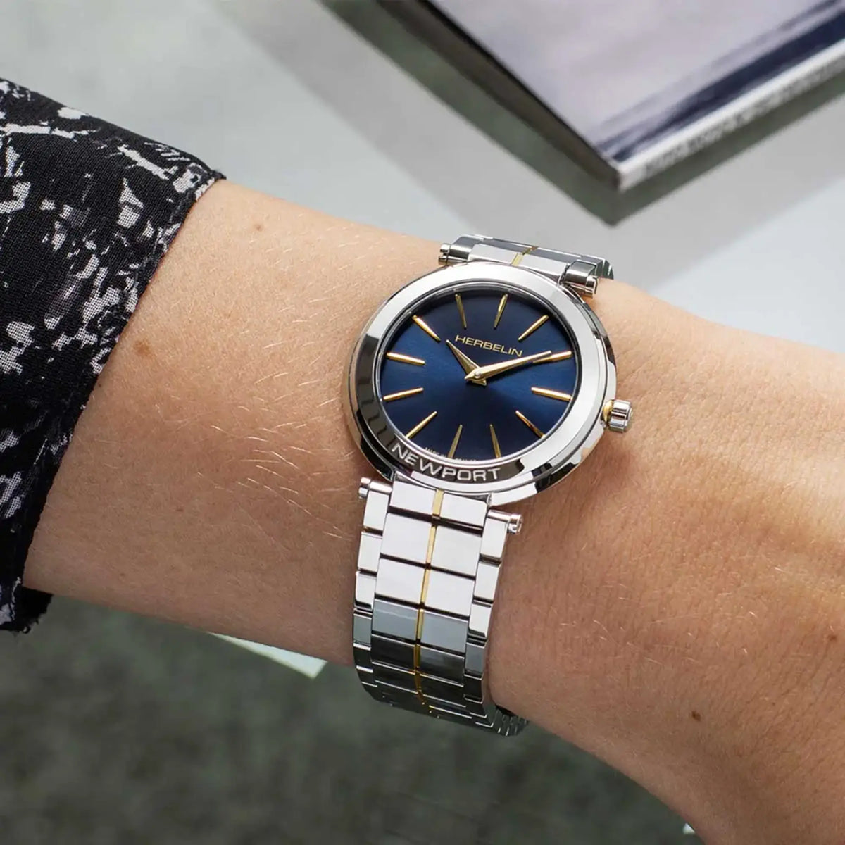 ⁣⁢Al polso femminile, un quadrante blu profondo e un bracciale bicolore in acciaio.⁤⁣