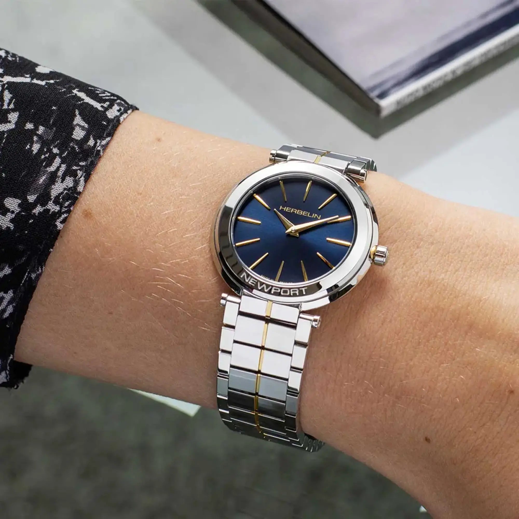 Au poignet féminin, cadran bleu profond et bracelet acier bicolore visibles