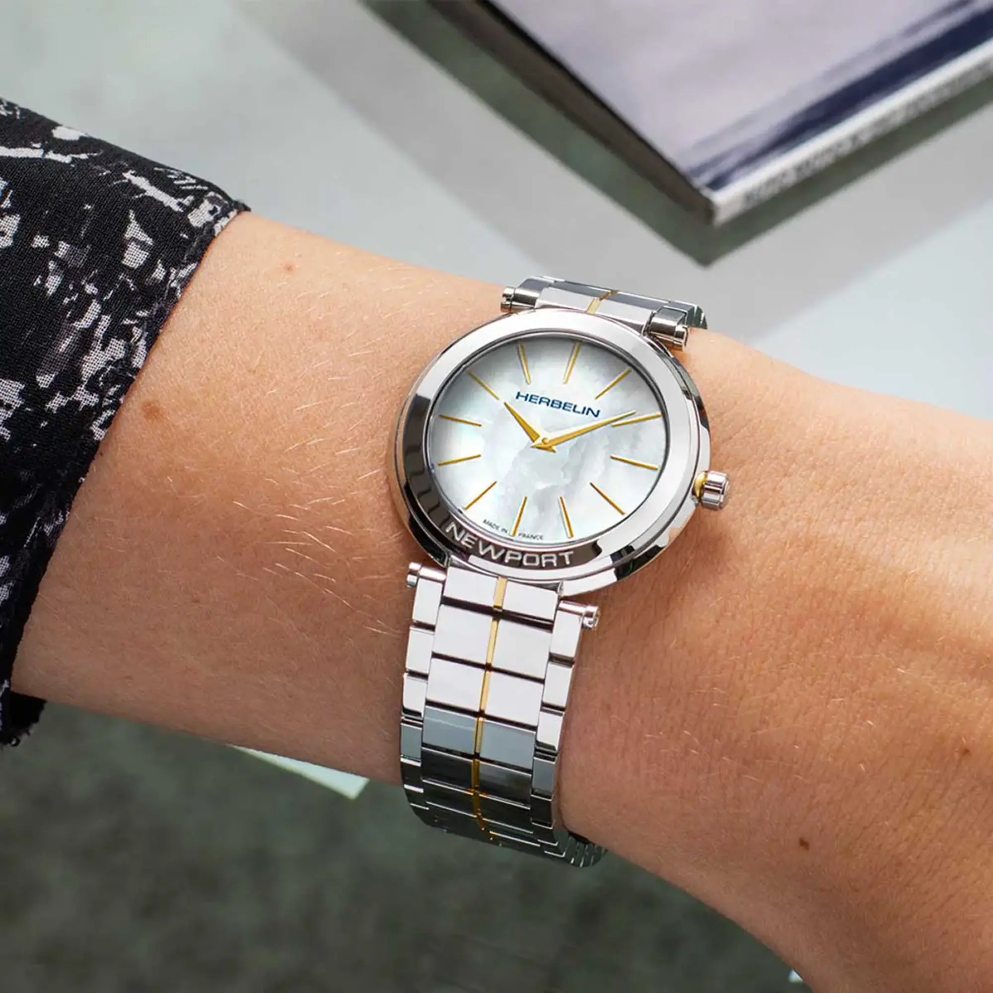 Au poignet féminin, cadran nacre blanche et bracelet acier bicolore visibles
