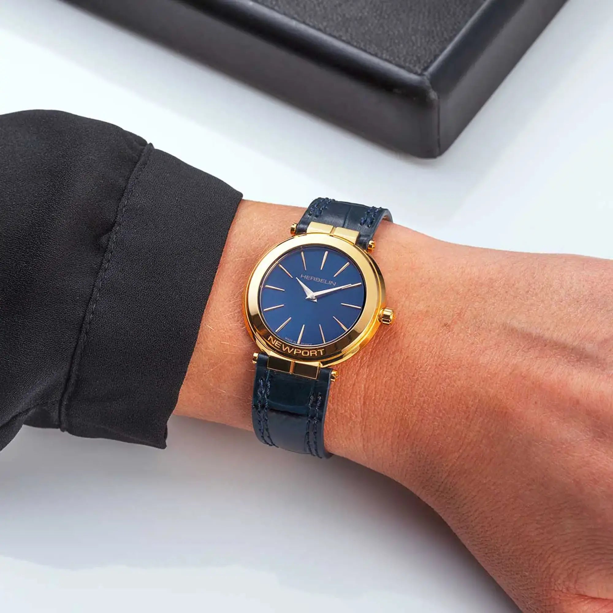 Au poignet féminin, cadran bleu profond et bracelet cuir visibles