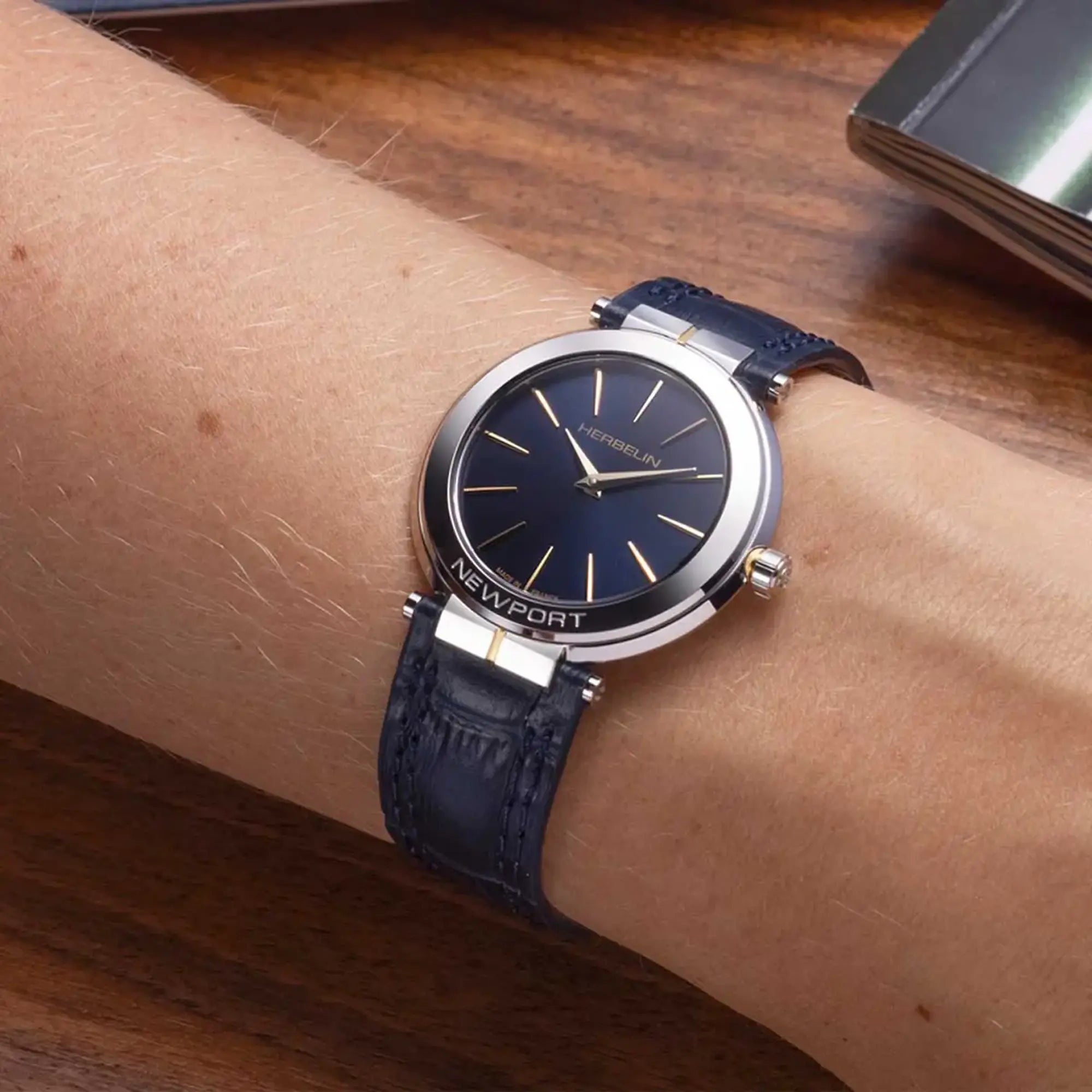 Au poignet féminin, cadran bleu profond et bracelet cuir visibles