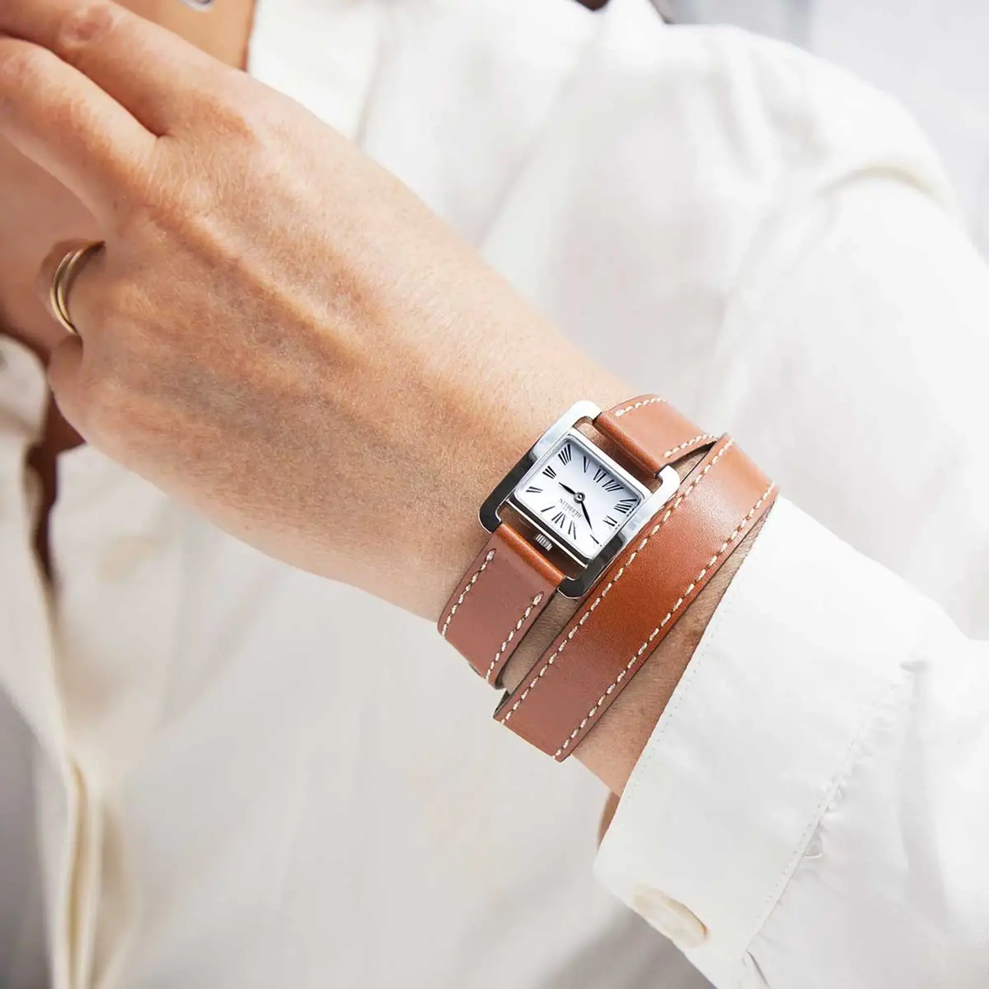 Au poignet féminin, cadran argent et bracelet cuir visibles