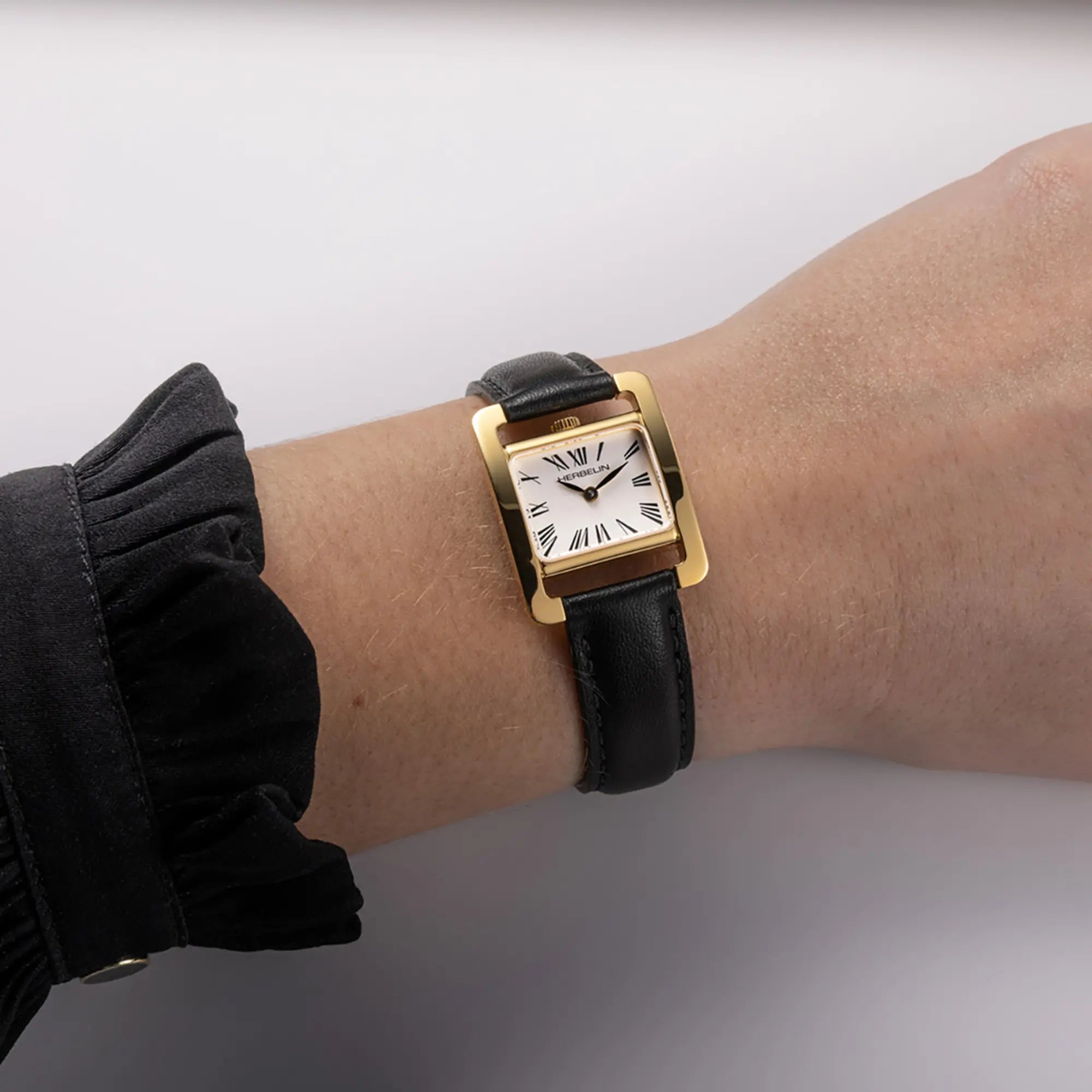 Au poignet féminin, cadran argent brossé vertical et bracelet cuir visibles