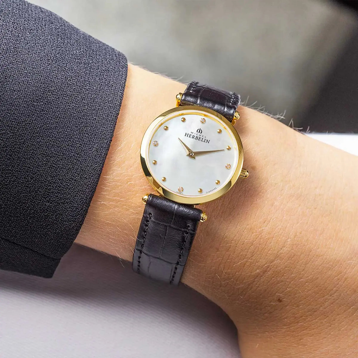 ⁣⁢On the feminine wrist, white mother-of-pearl dial and leather strap visible⁤⁣