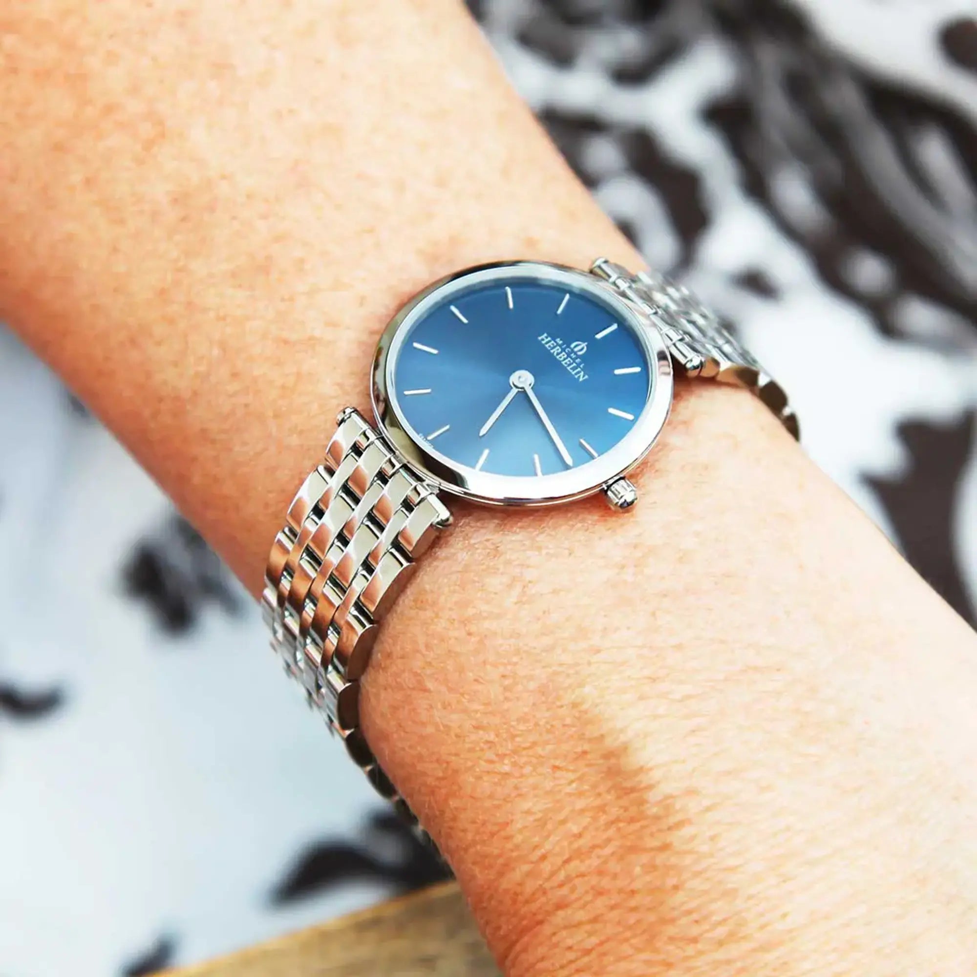 Au poignet féminin, cadran bleu et bracelet acier visibles