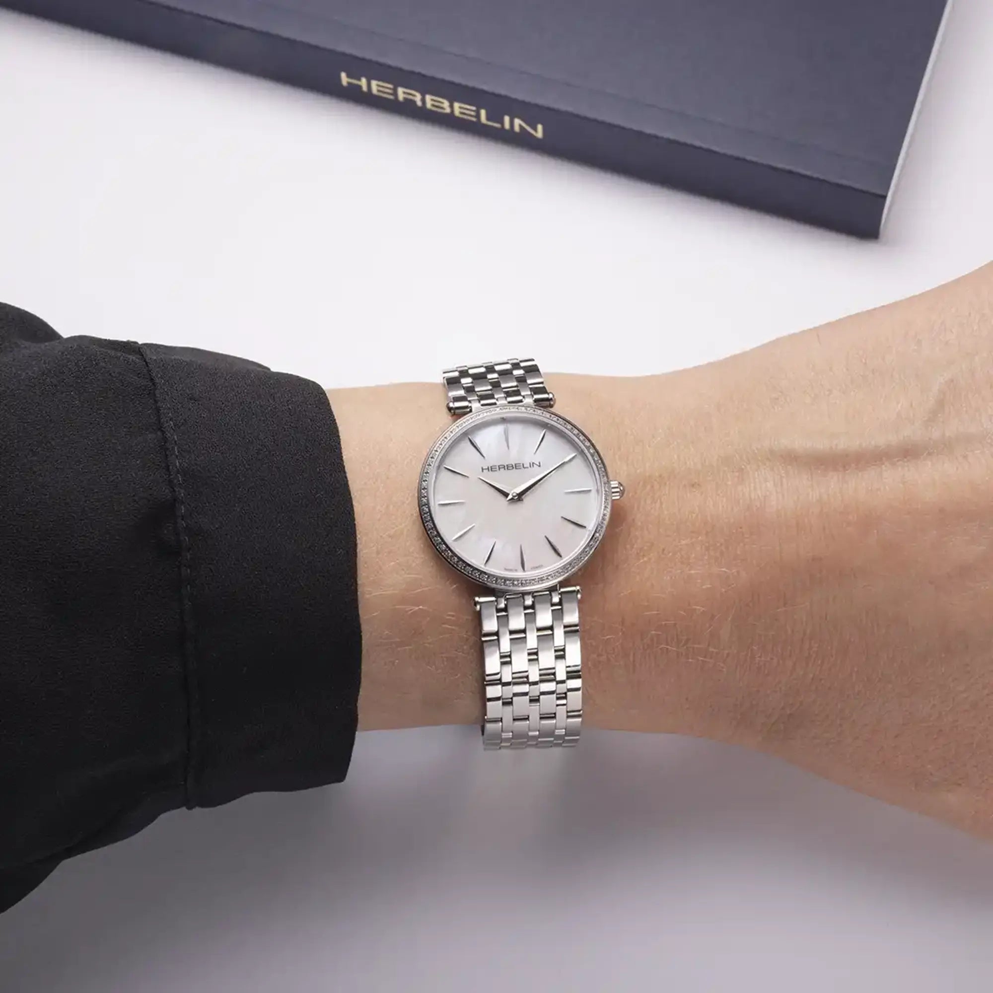 Au poignet féminin, cadran nacre blanche et bracelet acier visibles