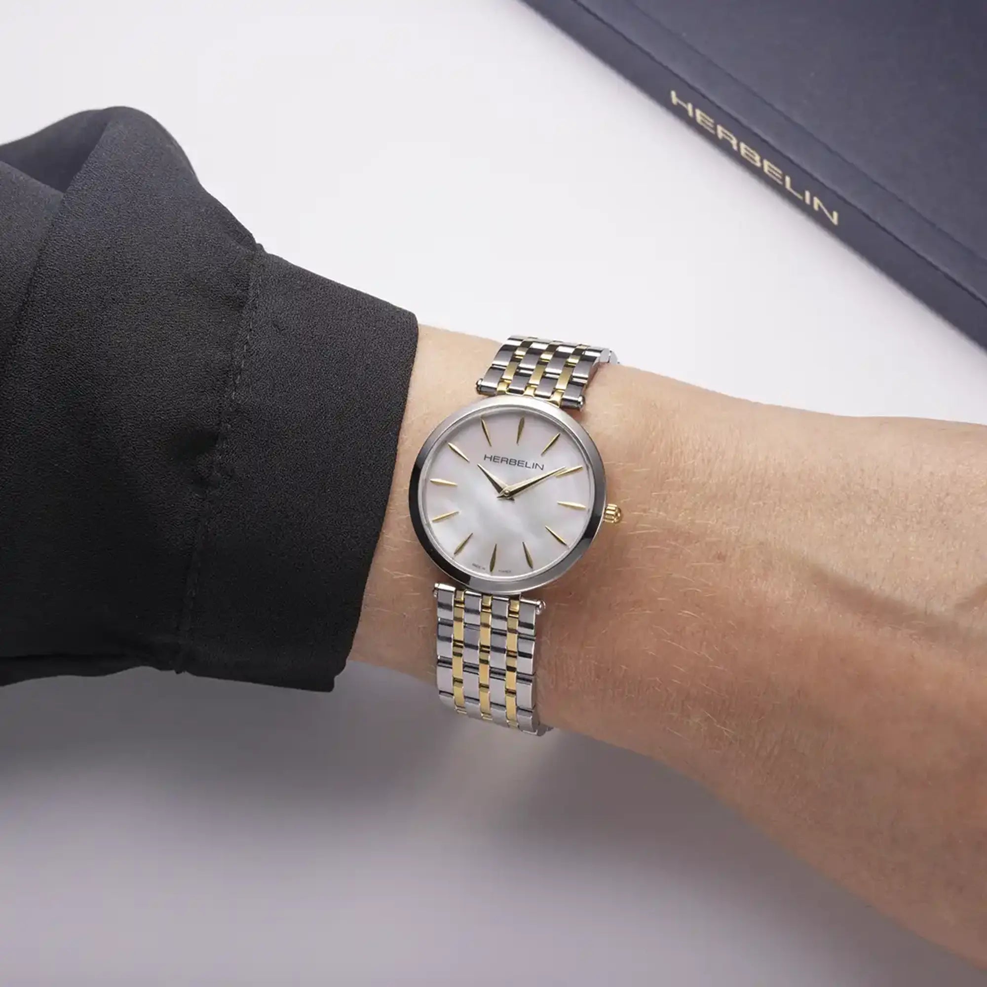 Au poignet féminin, cadran nacre blanche et bracelet acier bicolore visibles