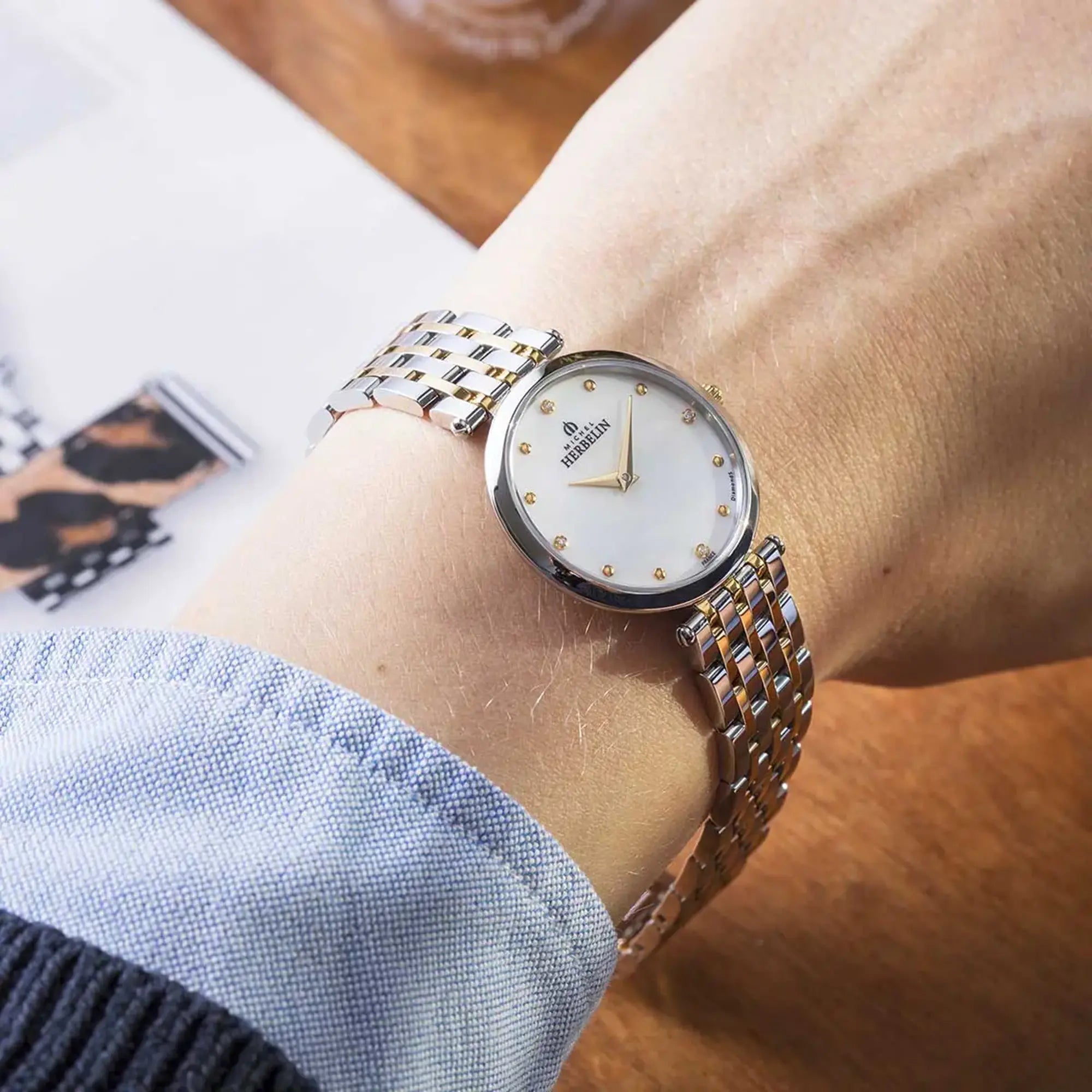 Au poignet féminin, cadran nacre blanche et bracelet acier bicolore visibles