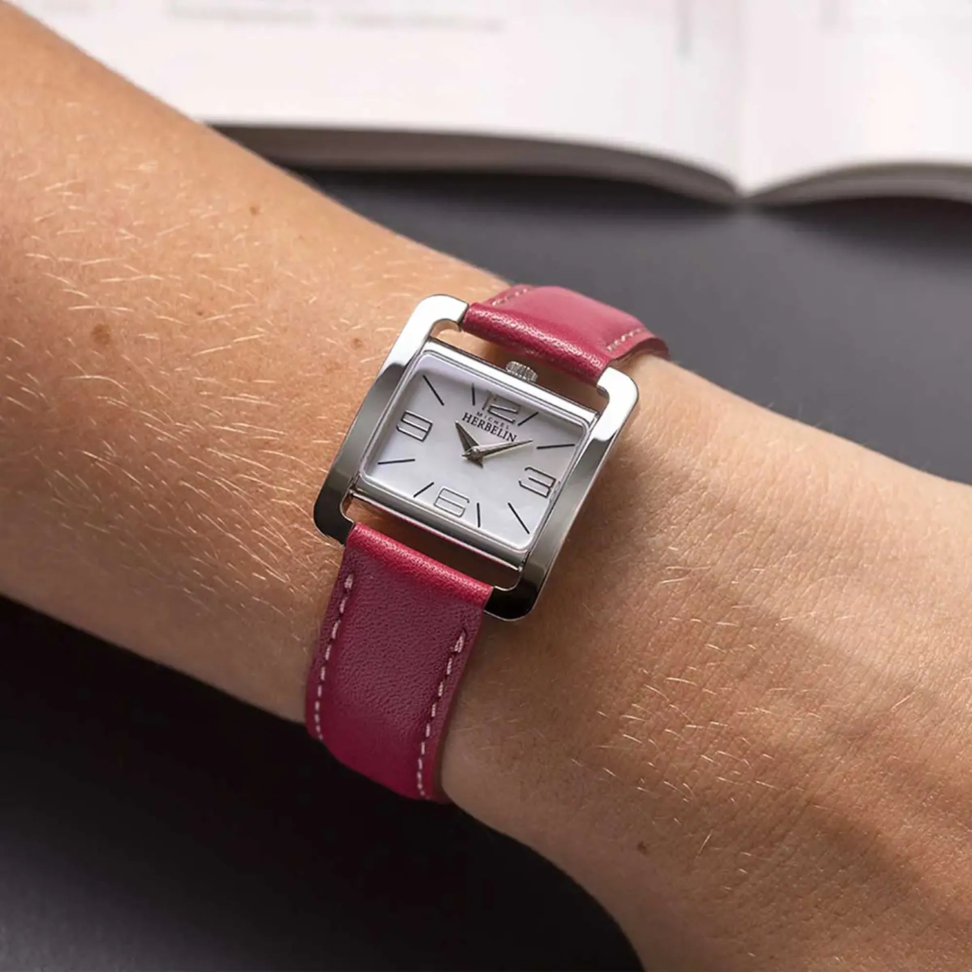 Au poignet féminin, cadran nacre blanche et bracelet cuir visibles