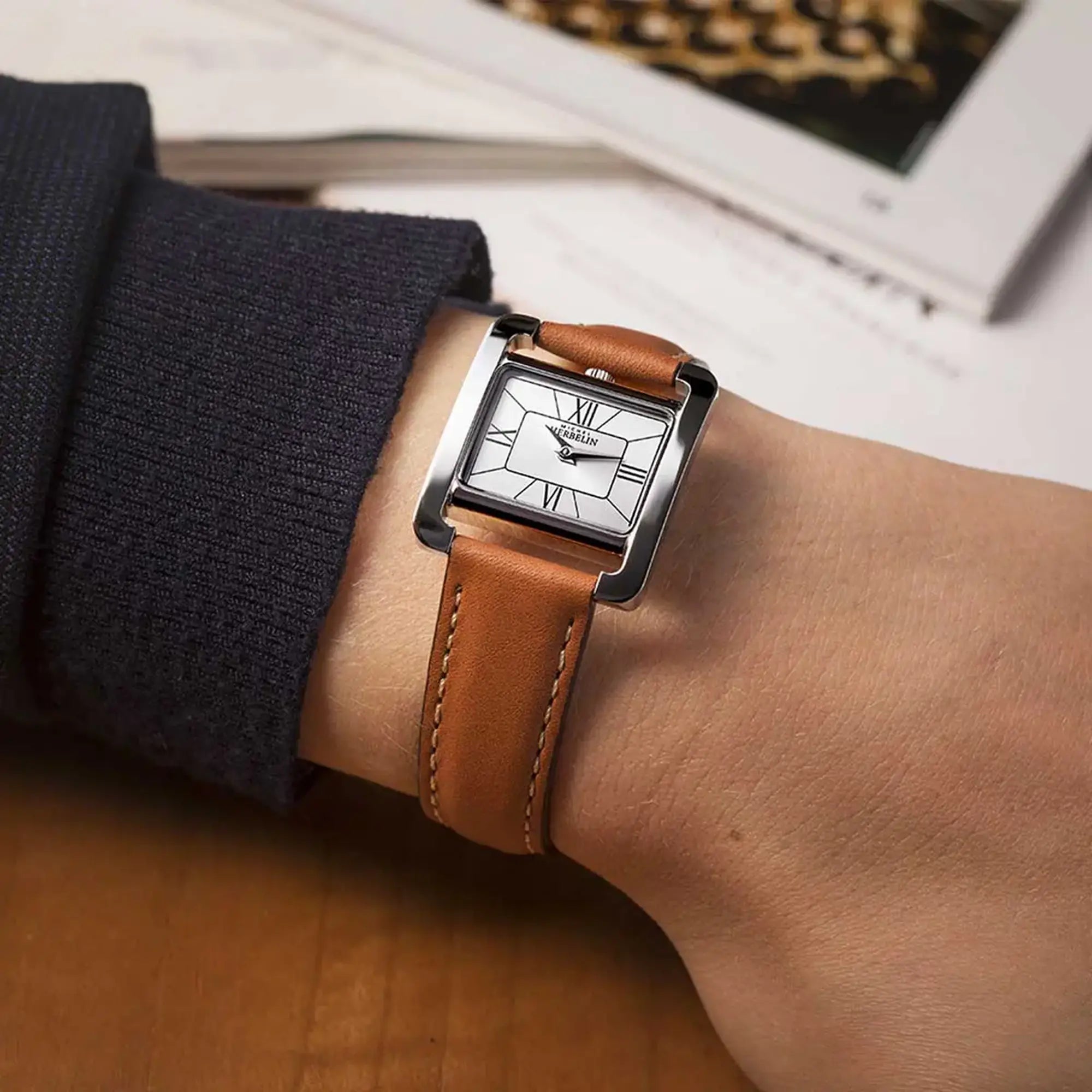 Au poignet féminin, cadran argent et bracelet cuir visibles