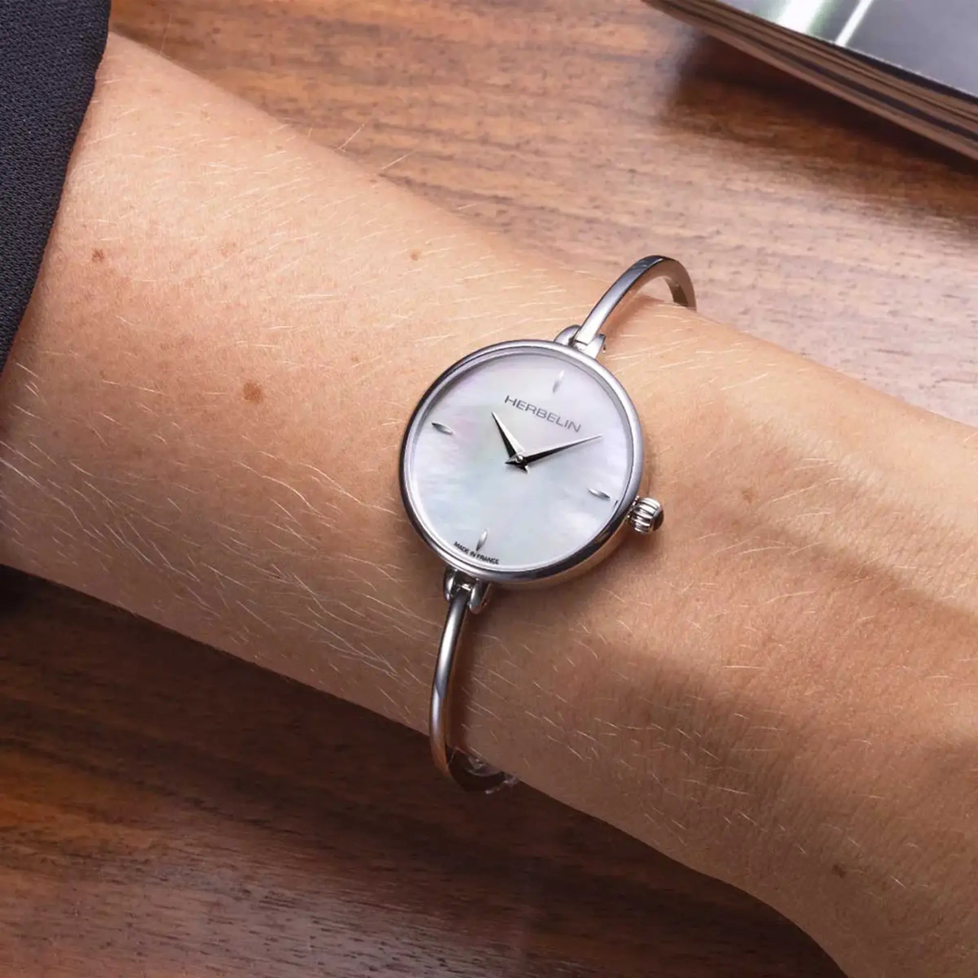 Au poignet féminin, cadran nacre blanche et bracelet acier visibles