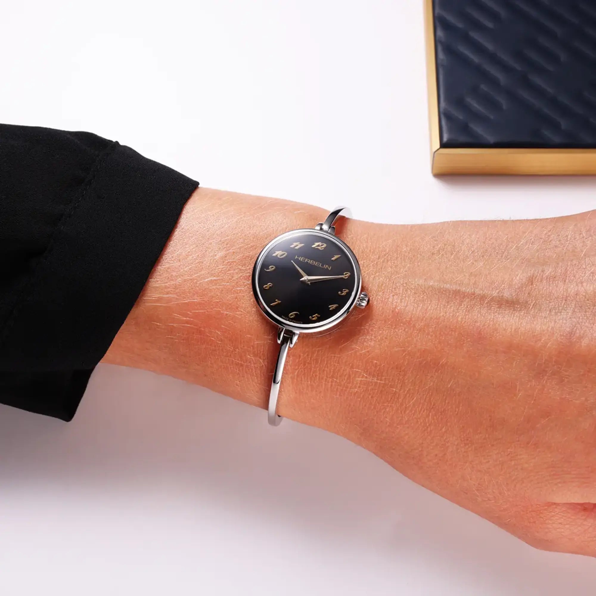 Au poignet féminin, cadran noir et bracelet acier visibles