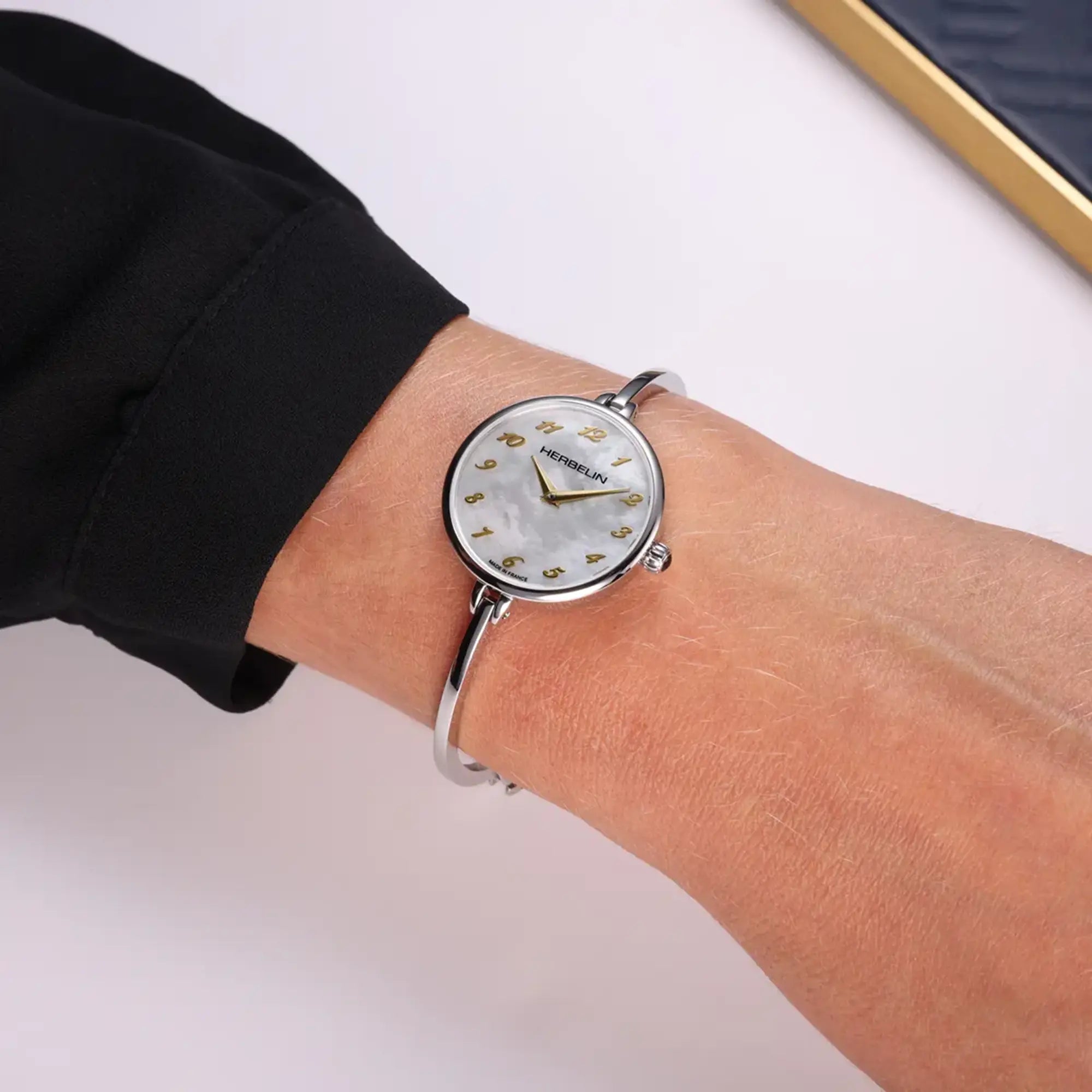 Au poignet féminin, cadran nacre blanche et bracelet acier visibles