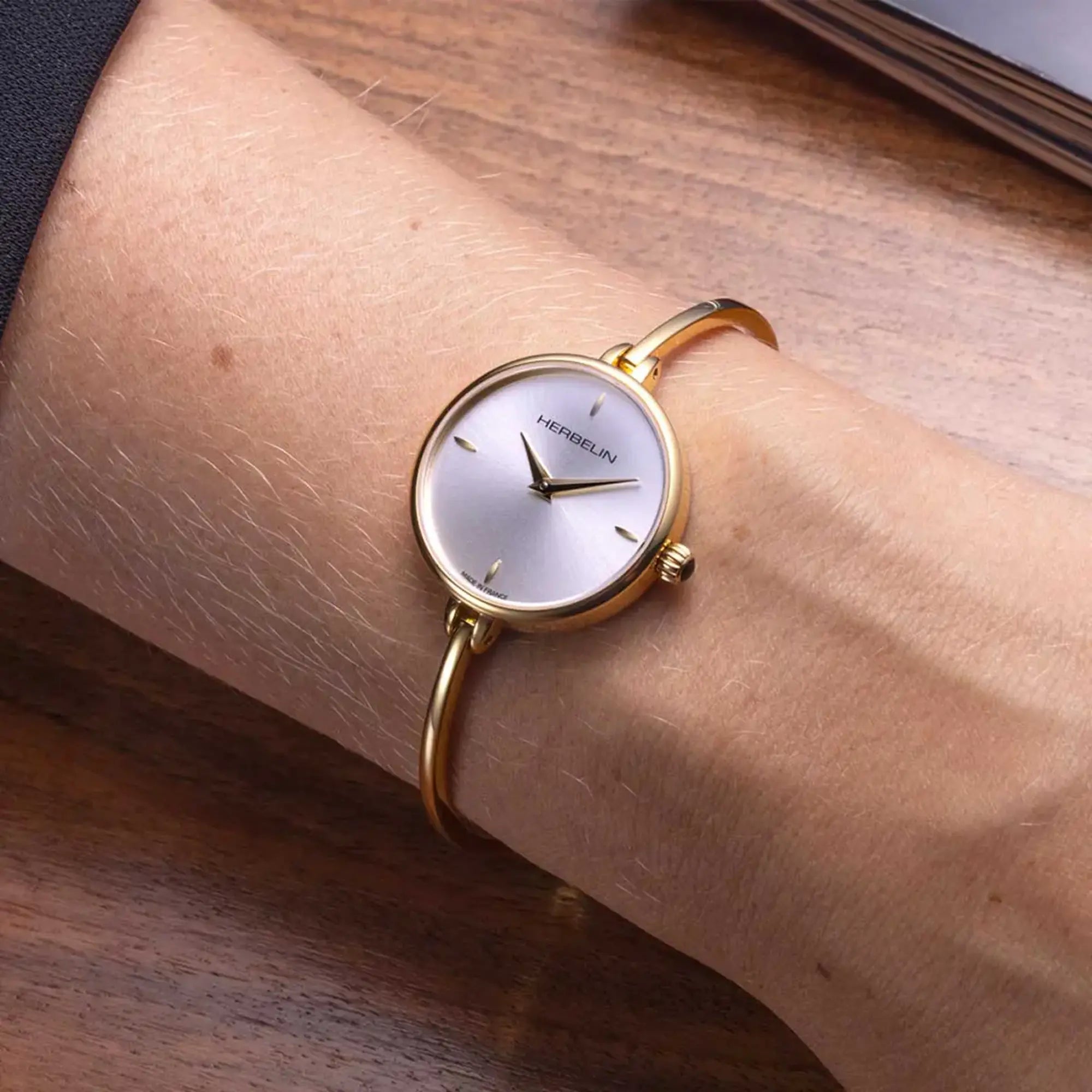 Au poignet féminin, cadran argent blanc et bracelet acier bicolore visibles
