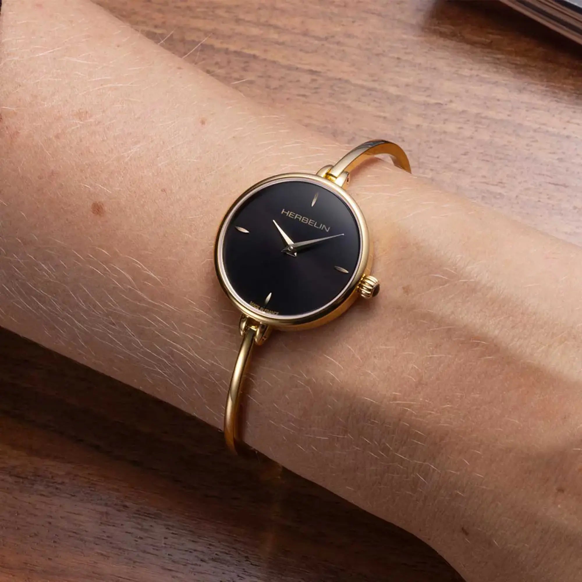Au poignet féminin, cadran noir et bracelet acier bicolore visibles