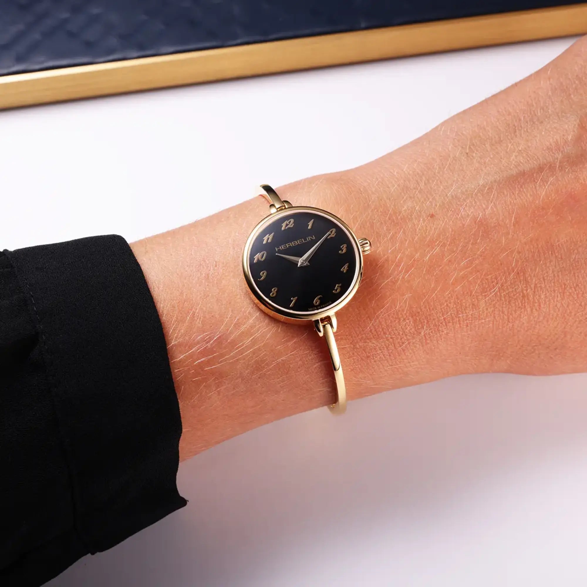 Au poignet féminin, cadran noir et bracelet acier bicolore visibles