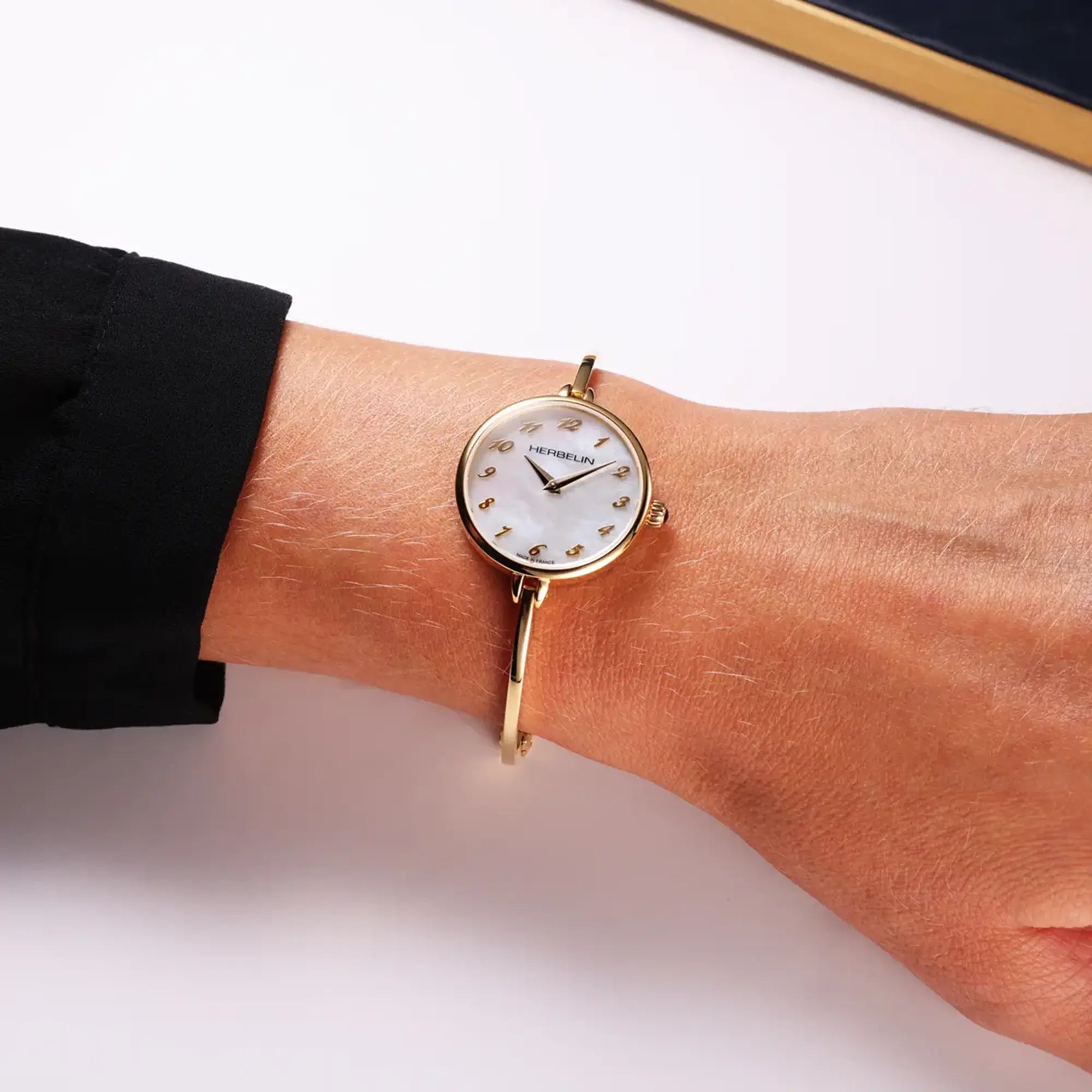 Au poignet féminin, cadran nacre blanche et bracelet acier bicolore visibles
