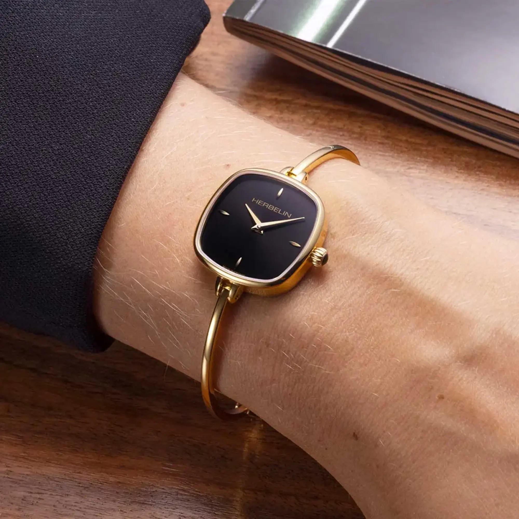 Au poignet féminin, cadran noir et bracelet acier bicolore visibles
