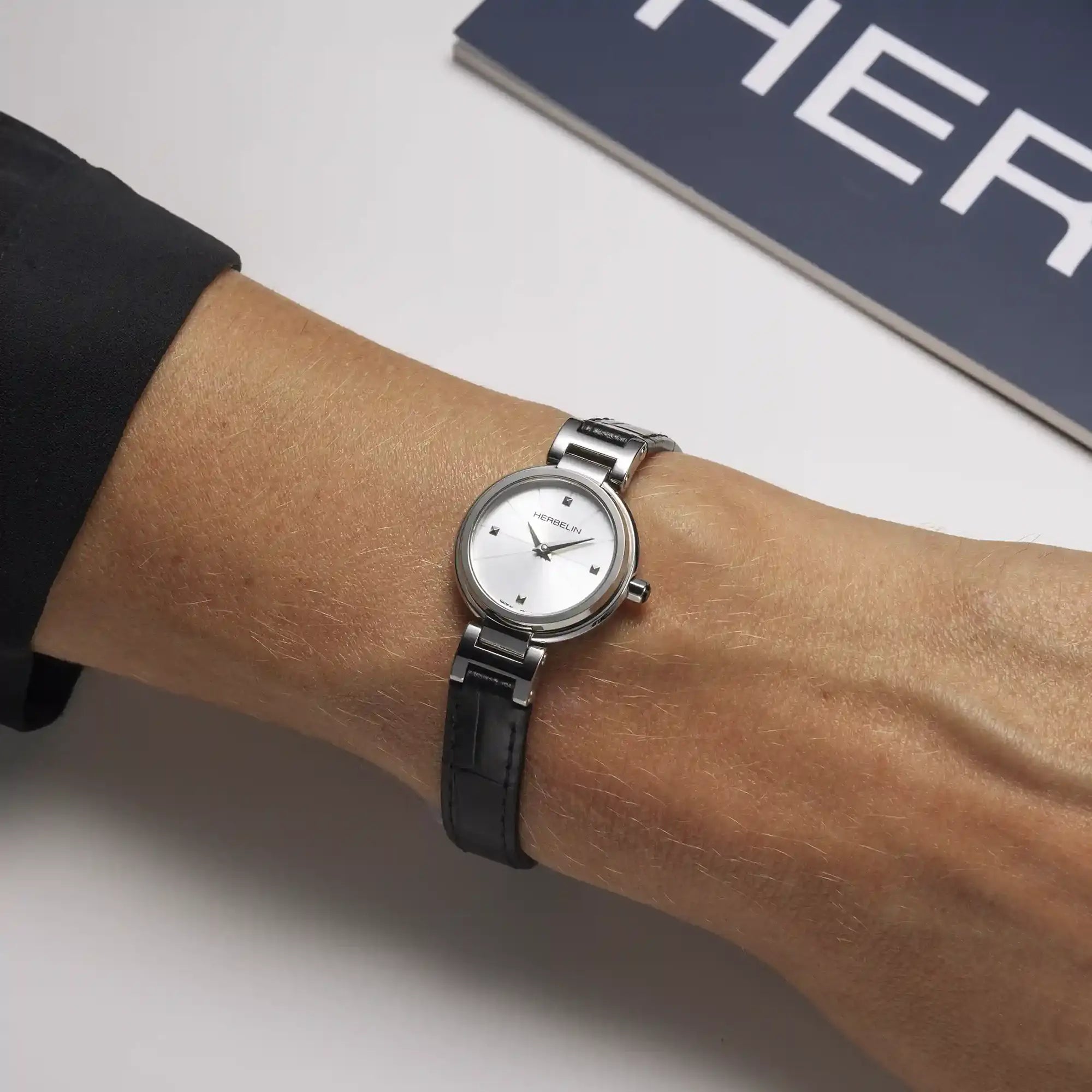 Au poignet féminin, cadran argent blanc et bracelet cuir visibles