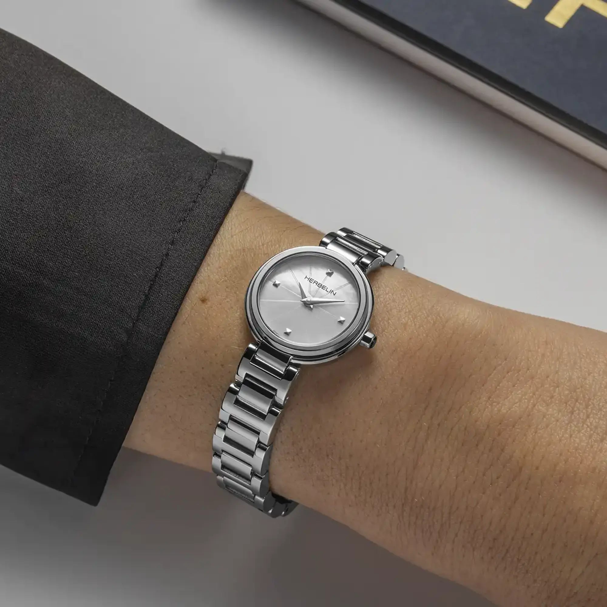 Au poignet féminin, cadran nacre blanche et bracelet acier visibles