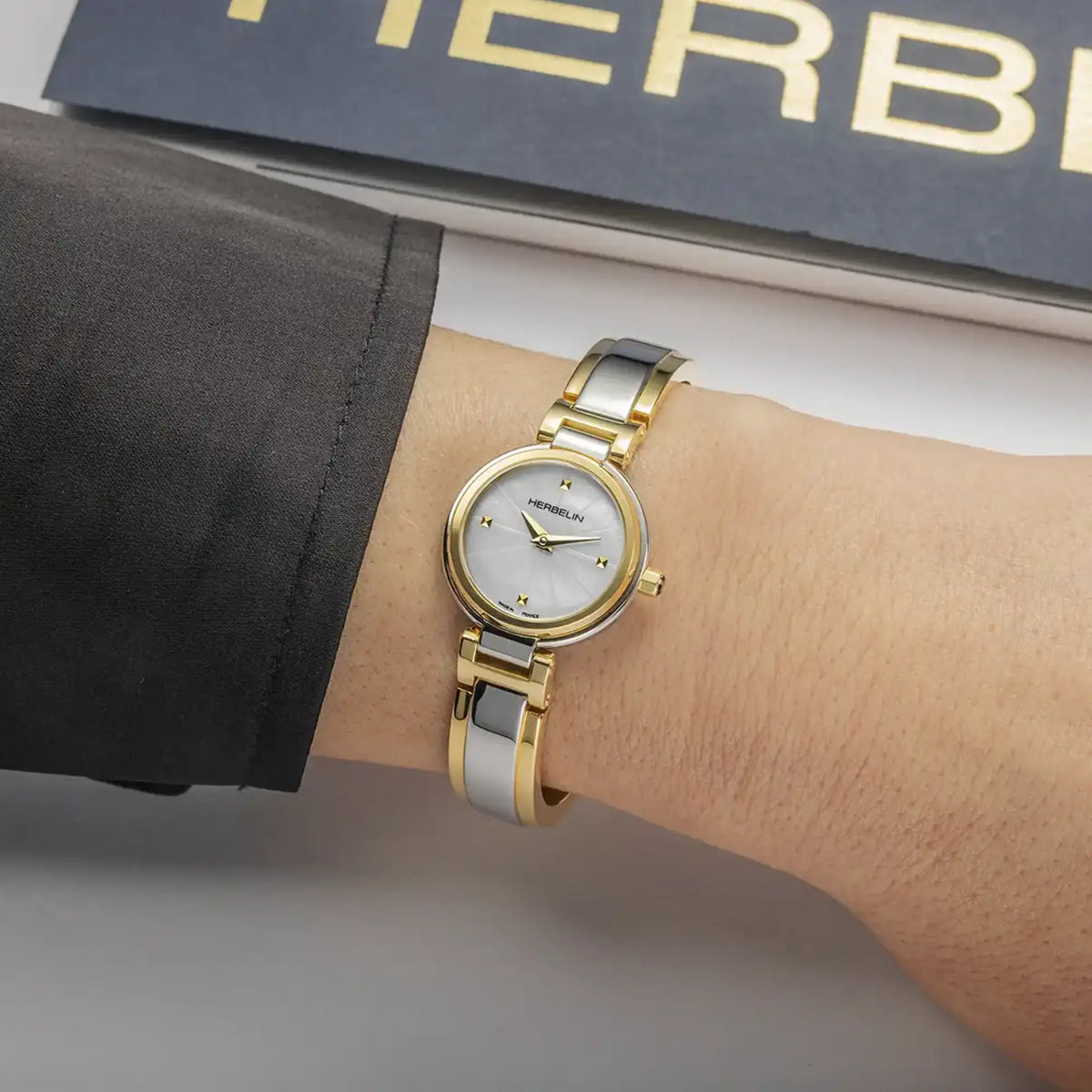 ⁣⁢En la muñeca femenina, esfera nácar blanco y brazalete de acero bicolor visibles⁤⁣