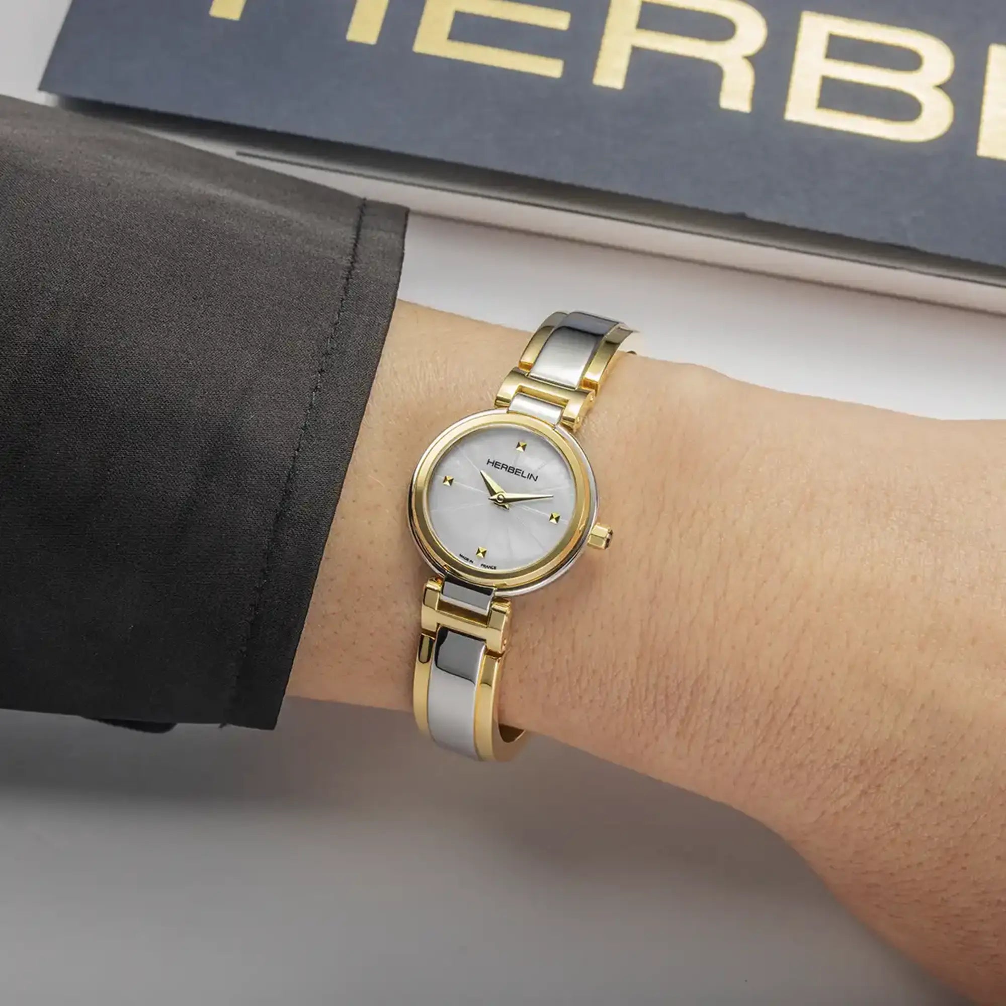 Au poignet féminin, cadran nacre blanche et bracelet acier bicolore visibles