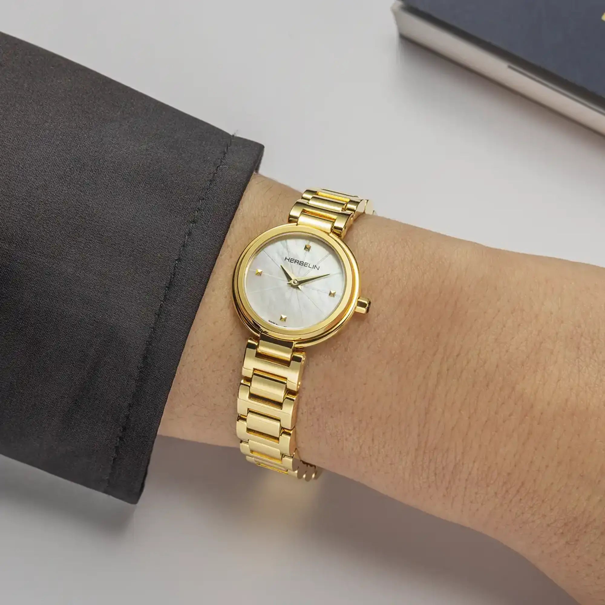 Au poignet féminin, cadran nacre blanche et bracelet acier bicolore visibles