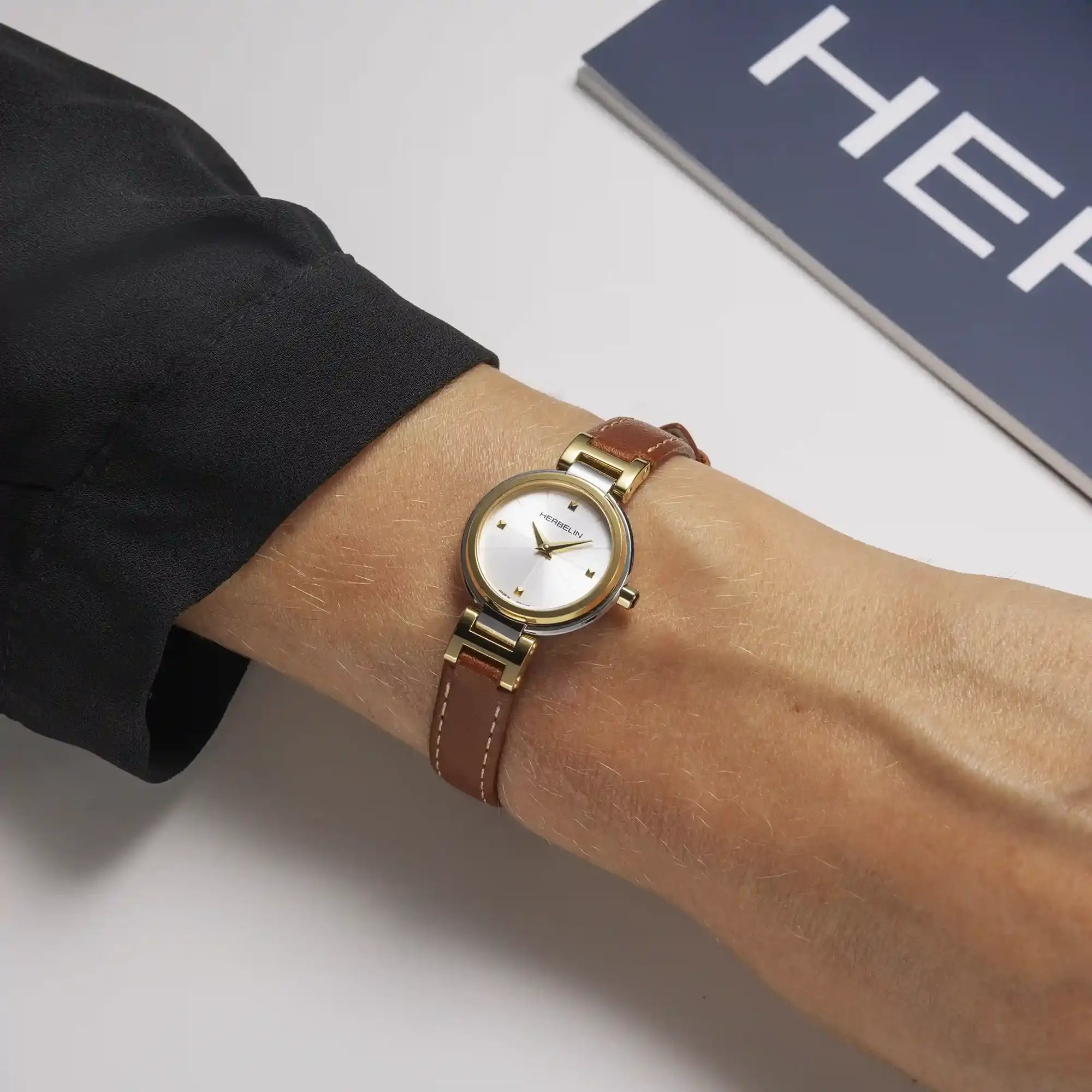 Au poignet féminin, cadran argent blanc et bracelet cuir visibles