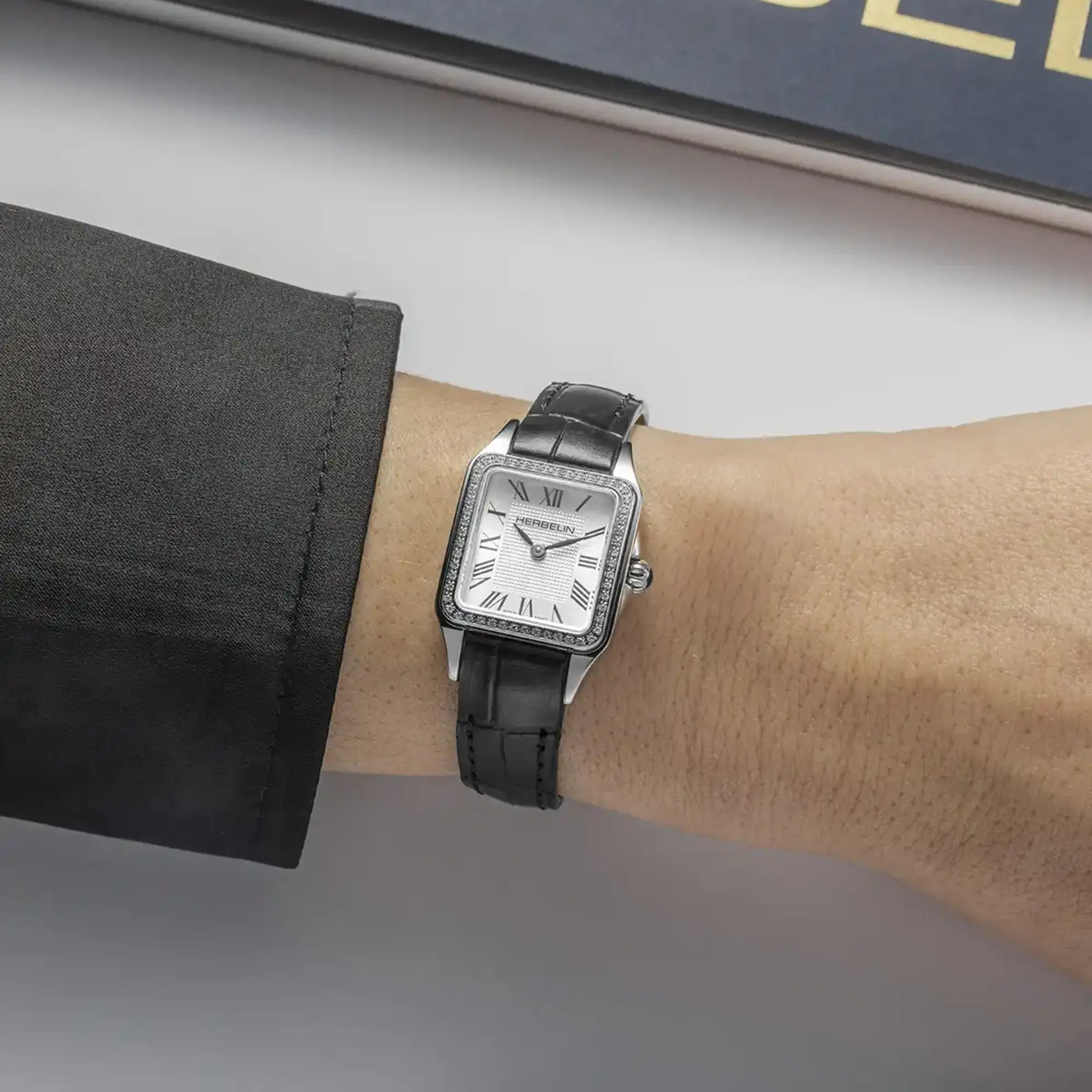 Au poignet féminin, cadran argent blanc et bracelet cuir visibles