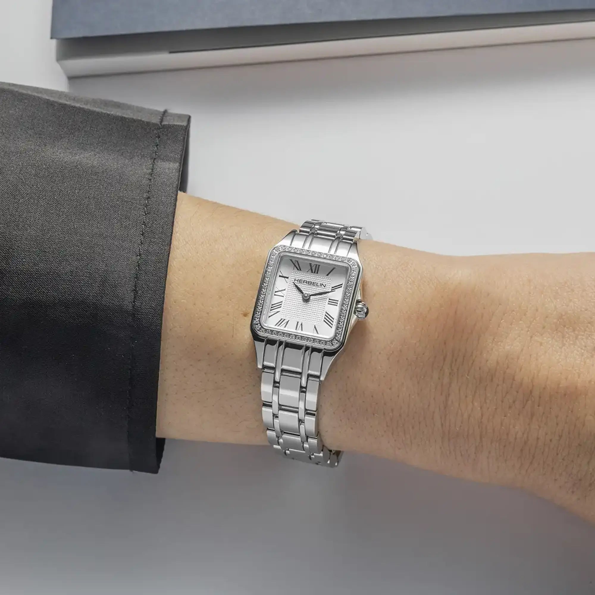 Au poignet féminin, cadran argent blanc et bracelet acier visibles