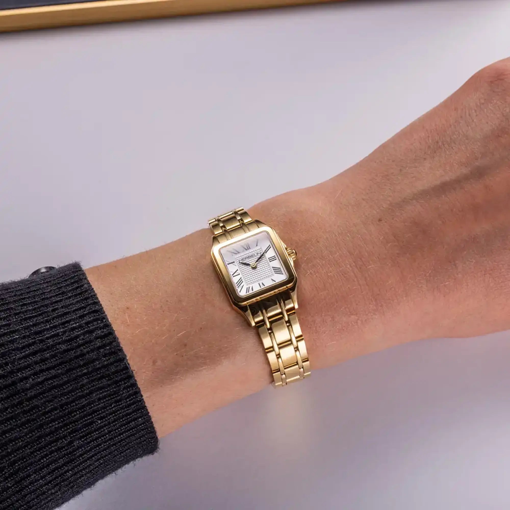 Au poignet féminin, cadran argent guilloché et bracelet caoutchouc visibles