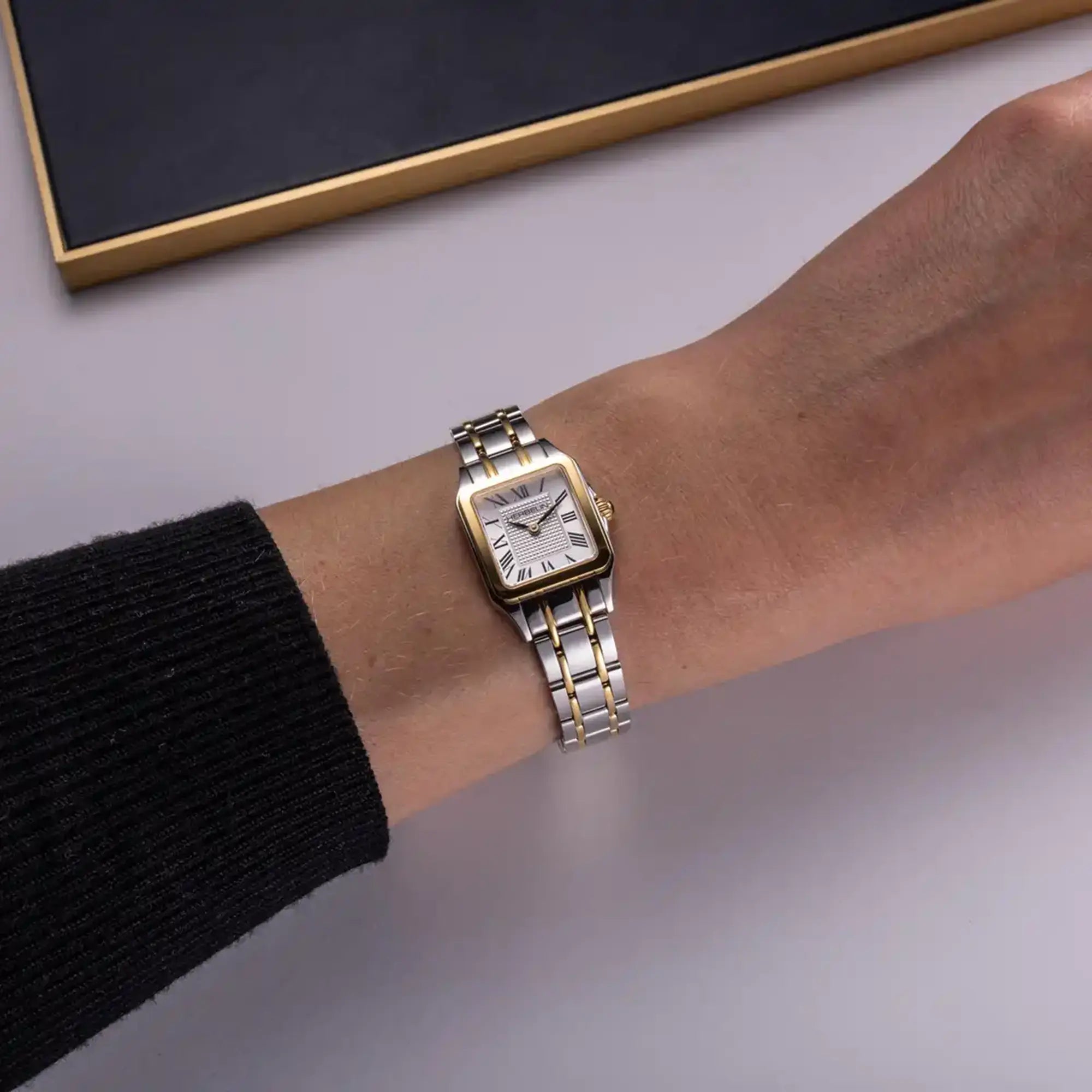 Au poignet féminin, cadran argent guilloché et bracelet acier bicolore visibles