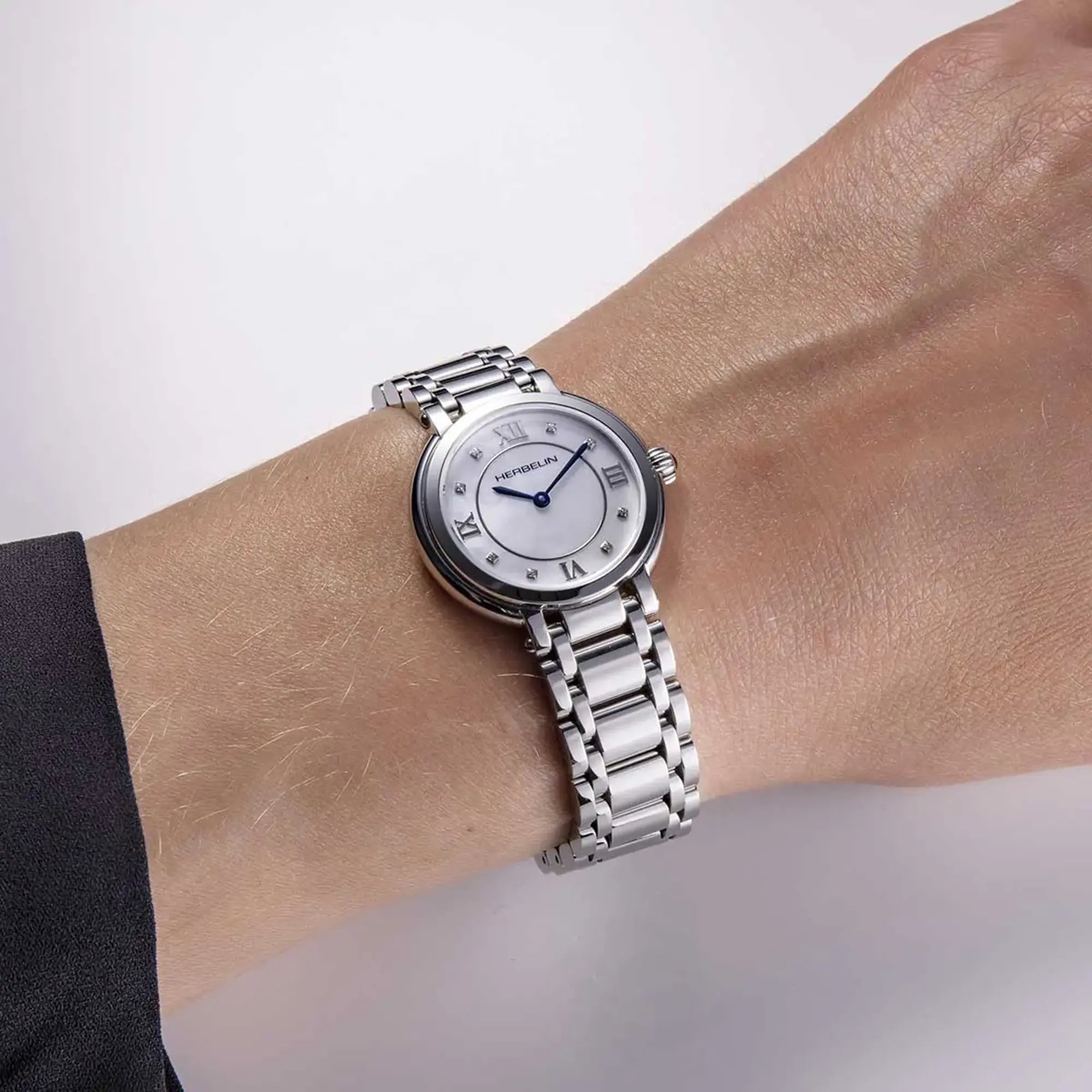 Au poignet féminin, cadran nacre blanche et bracelet acier visibles