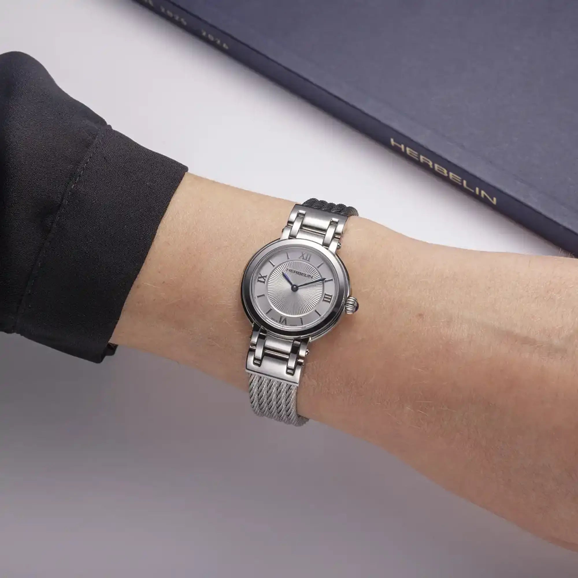 Au poignet féminin, cadran argent guilloché et bracelet acier visibles