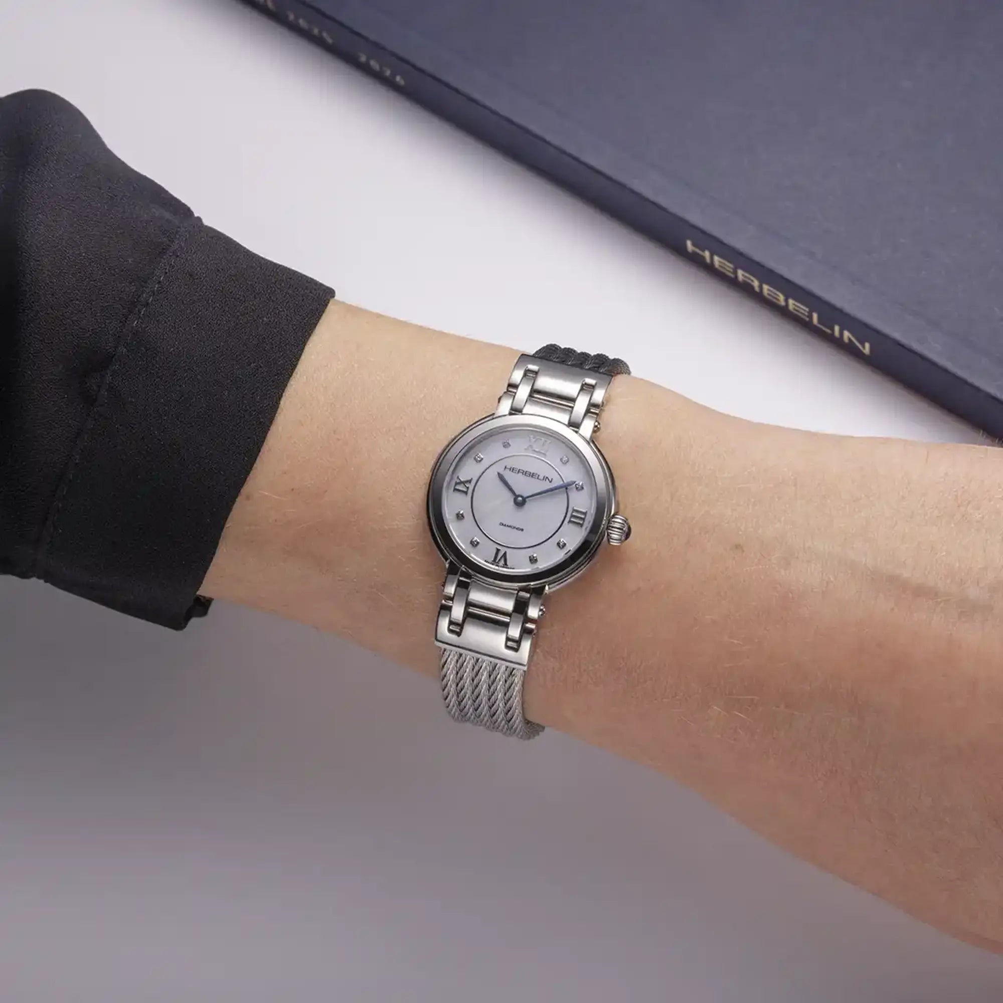 Au poignet féminin, cadran nacre blanche et bracelet acier visibles