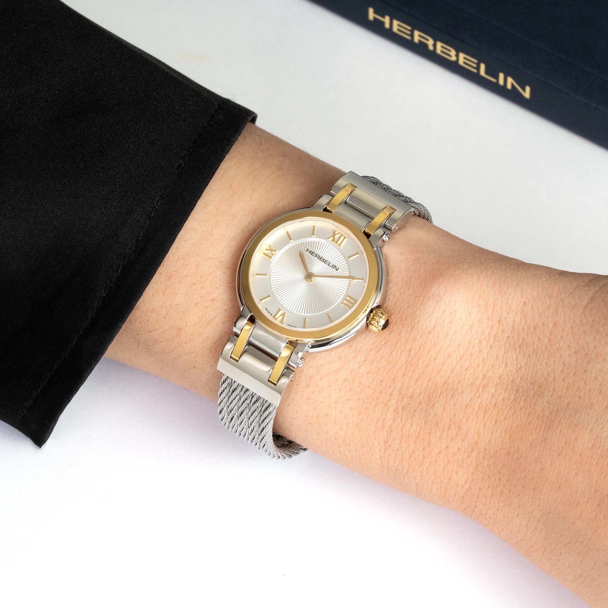 Au poignet féminin, cadran blanc et bracelet milanais acier bicolore visibles