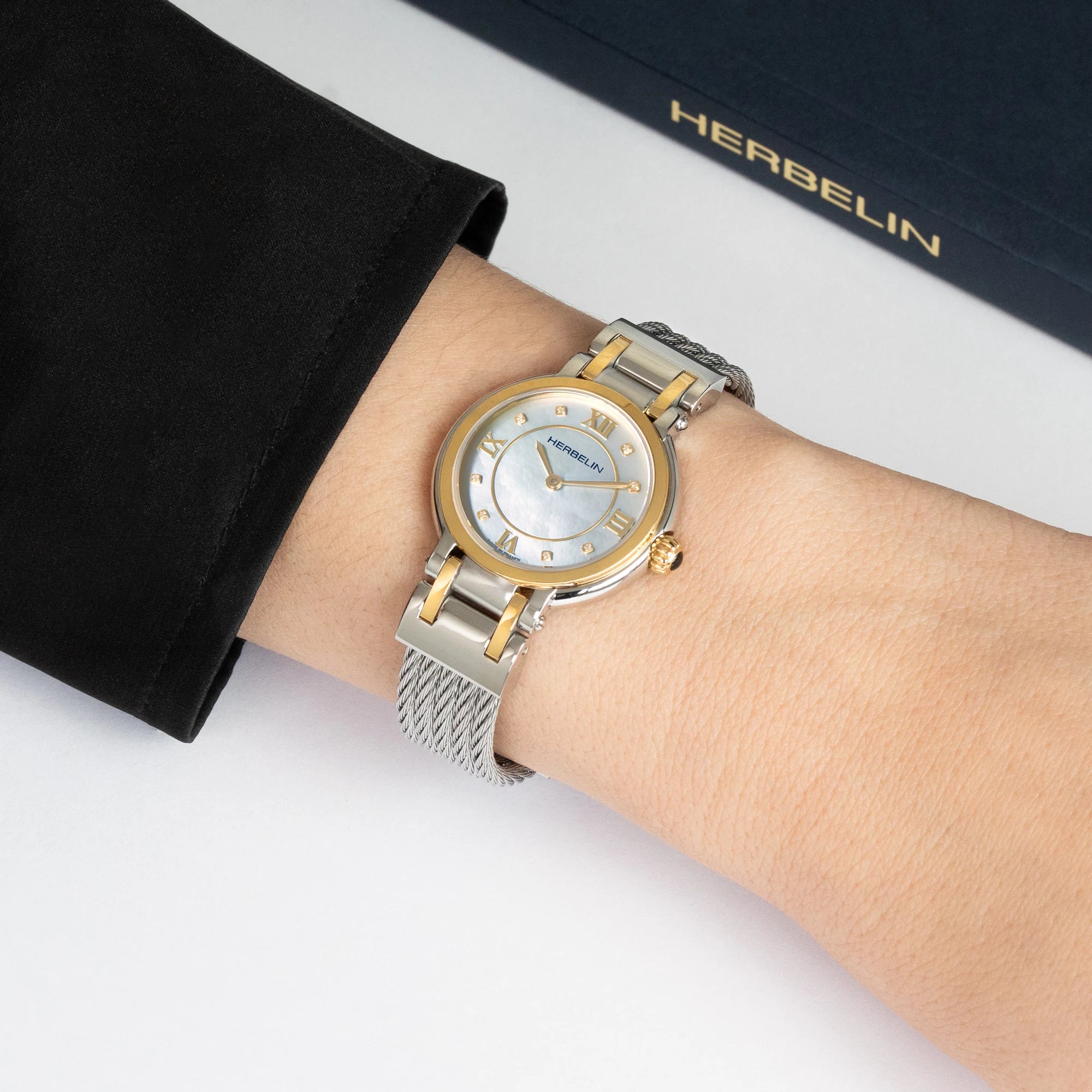 Au poignet féminin, cadran nacre et bracelet milanais acier bicolore visibles