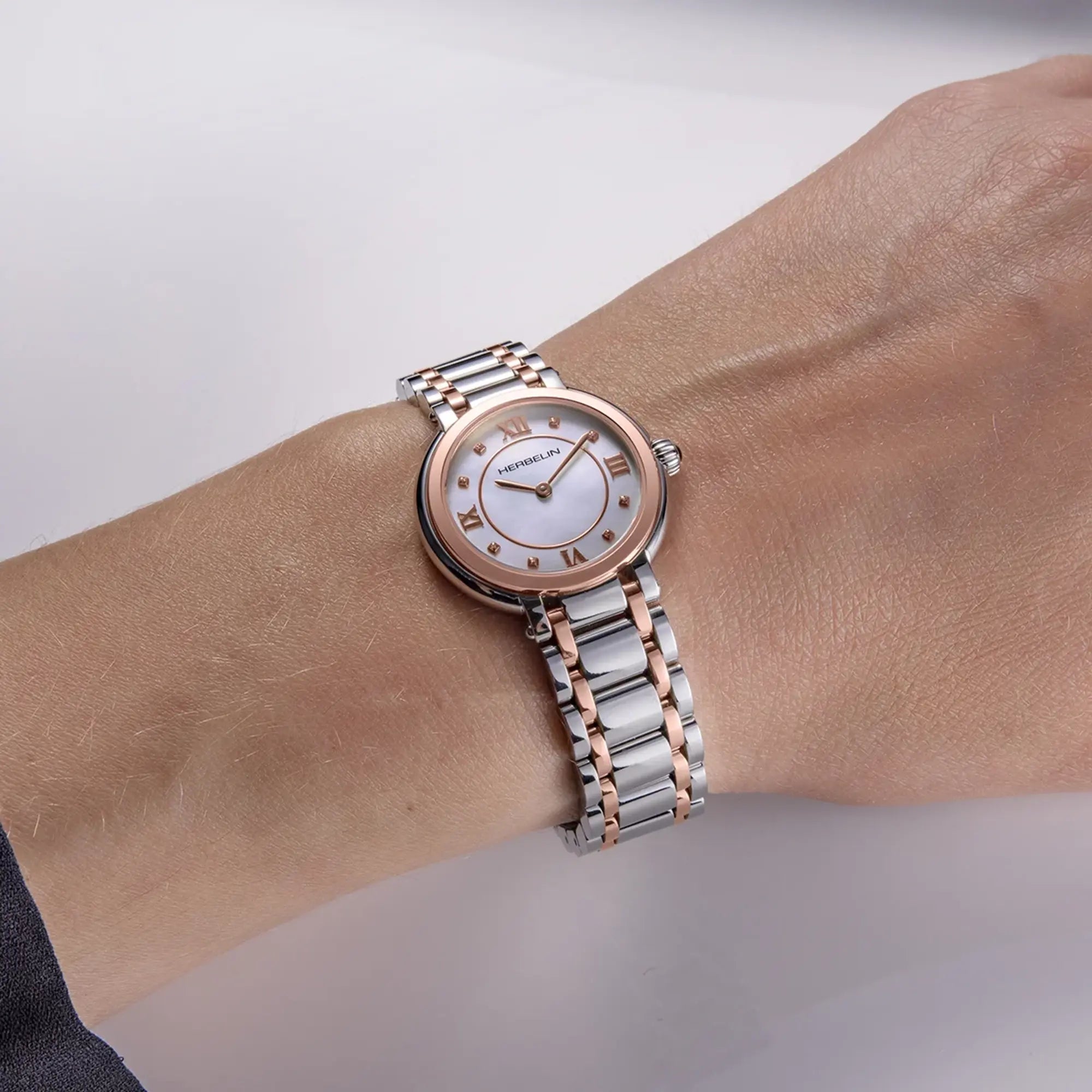Au poignet féminin, cadran nacre blanche et bracelet acier PVD or rose visibles