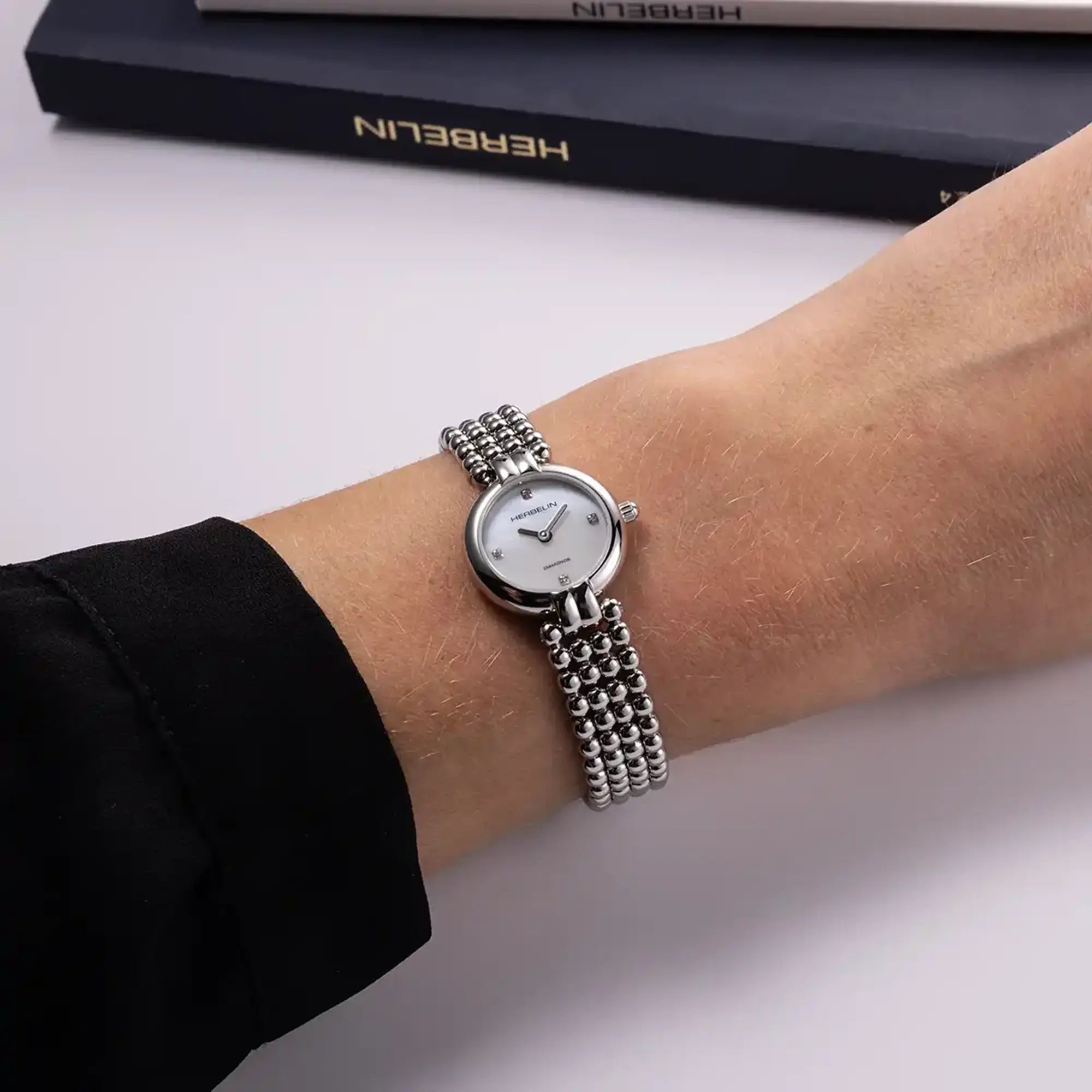 Au poignet féminin, cadran nacre blanche et bracelet acier bicolore visibles