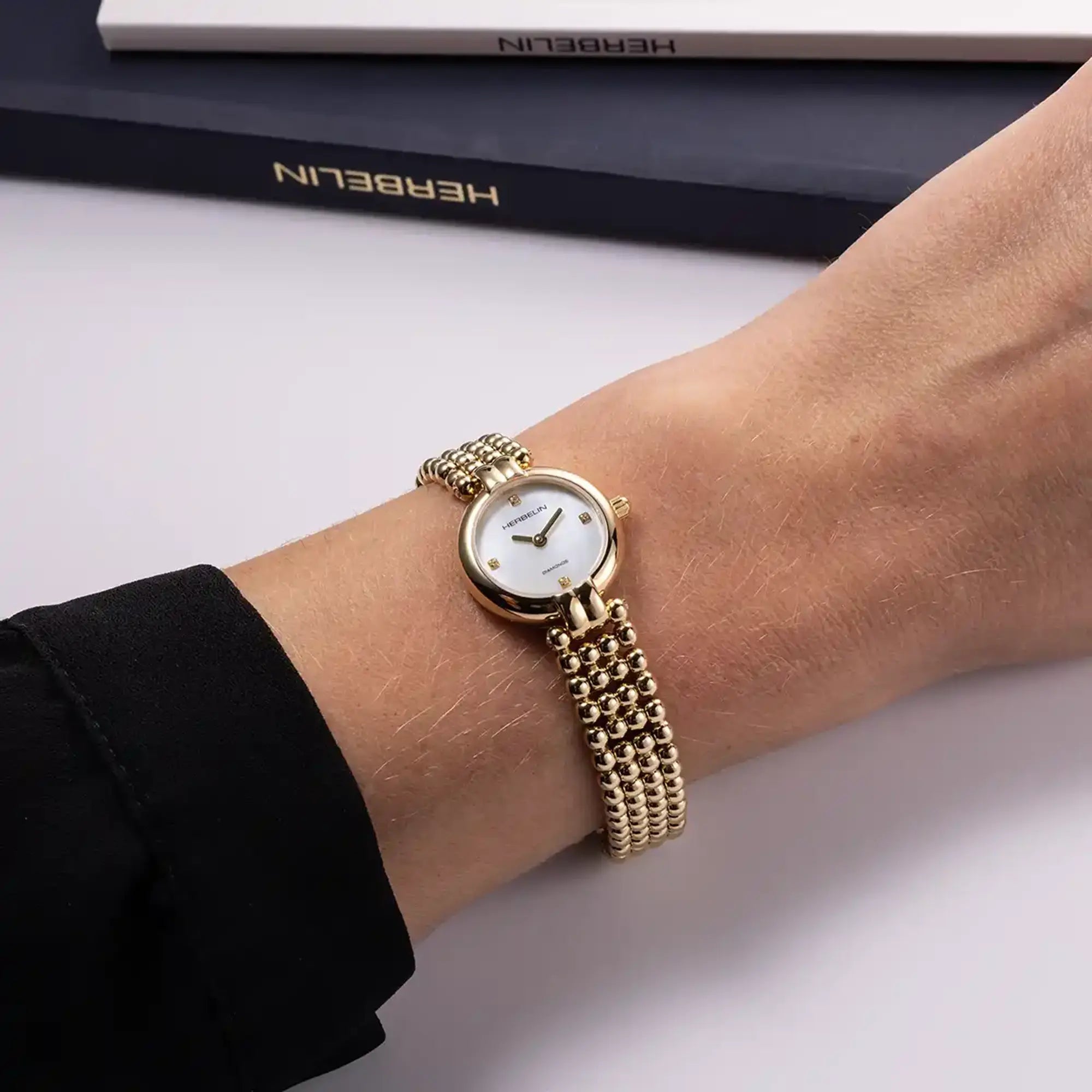 Au poignet féminin, cadran nacre blanche et bracelet acier bicolore visibles