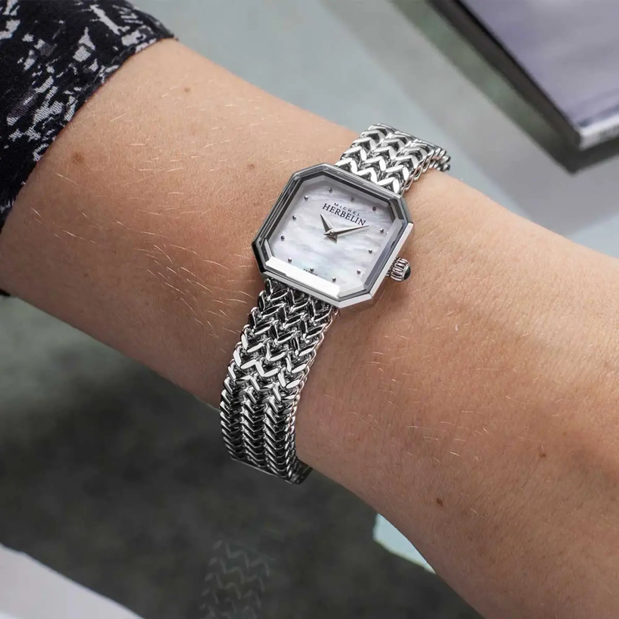 Au poignet féminin, cadran nacre blanche et bracelet acier visibles