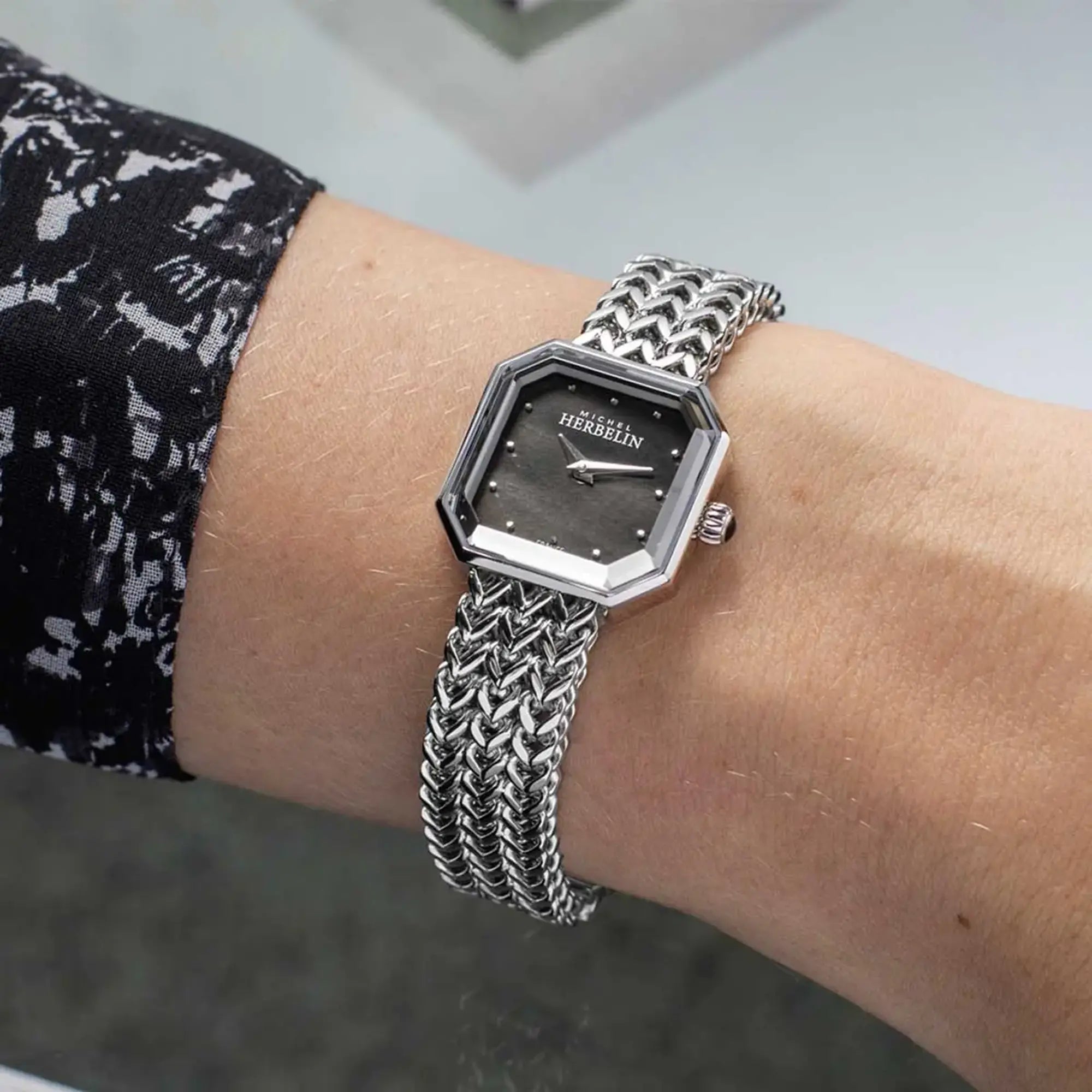 Au poignet féminin, cadran nacre noire et bracelet acier visibles