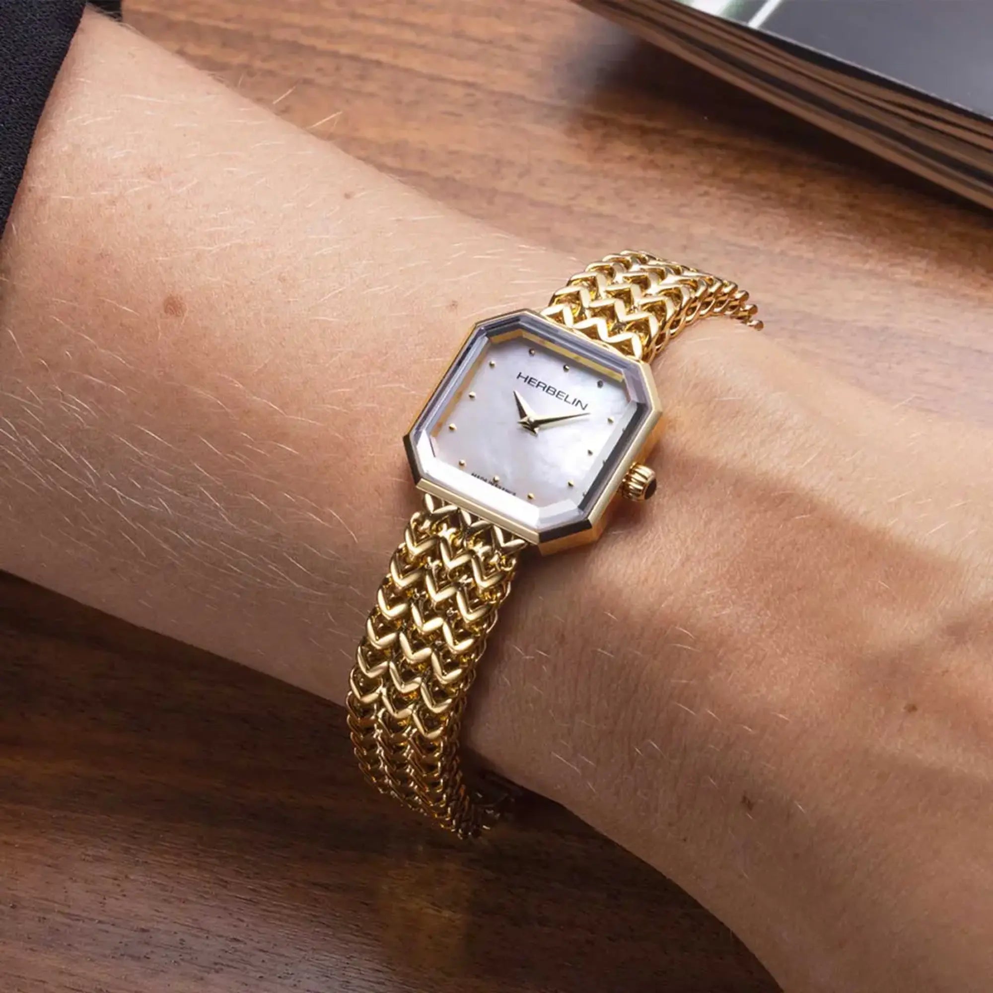 Au poignet féminin, cadran nacre blanche et bracelet acier bicolore visibles
