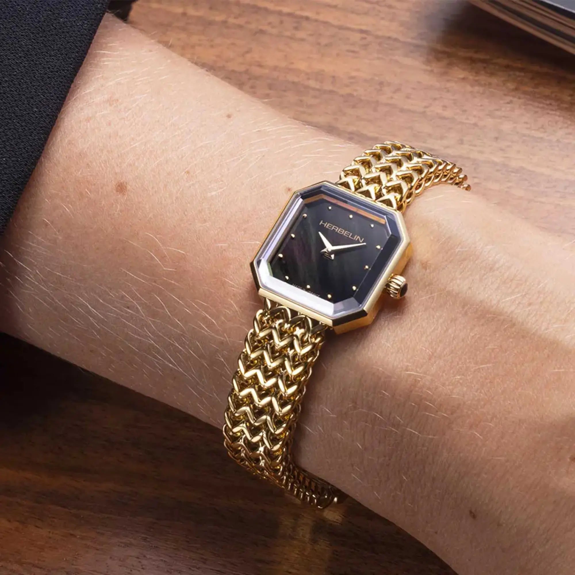 Au poignet féminin, cadran nacre noire et bracelet acier bicolore visibles